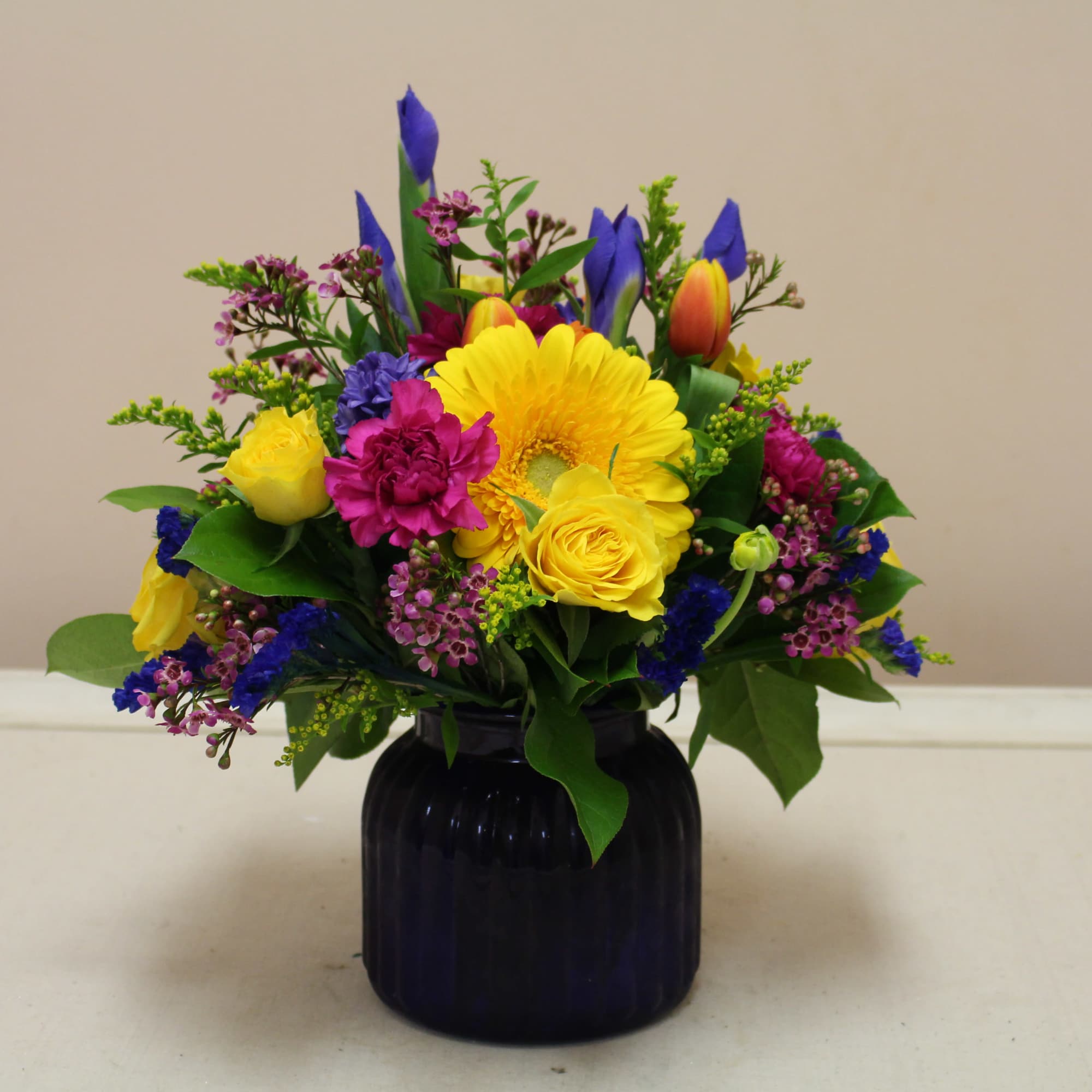 fresh arrangement in a blue cobalt vase filled with spring flowers