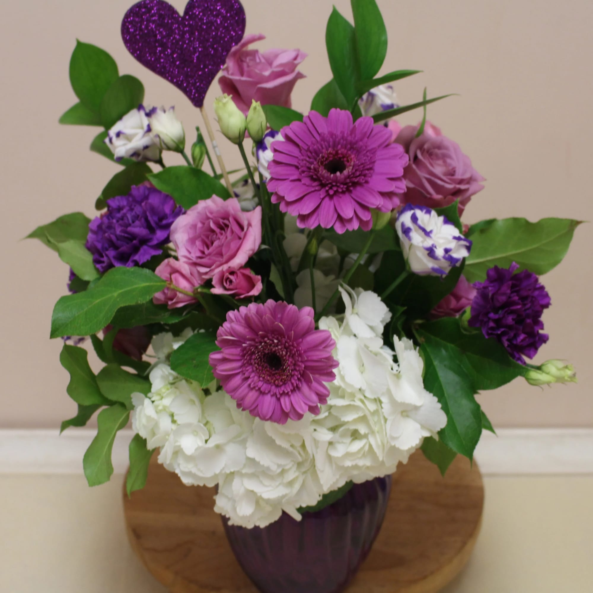 A purple vase filled with hydrangea, gerbera's, floregene and more 
great for
