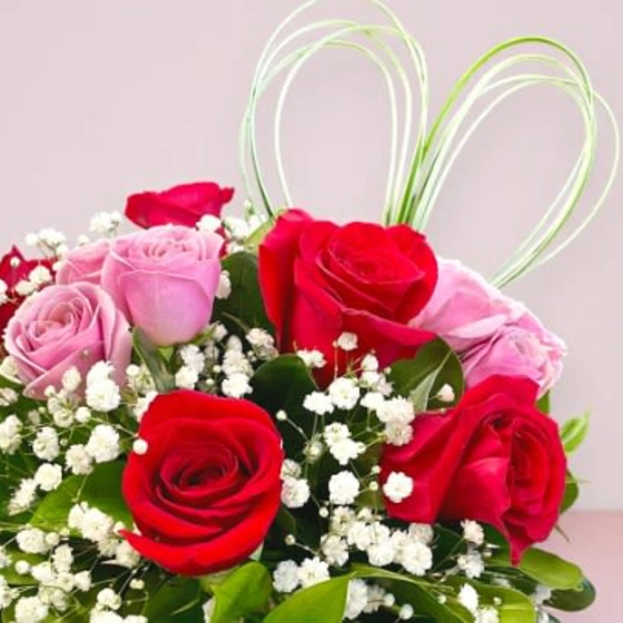 This Valentine's Day arrangement showcases six red roses and purple spray roses