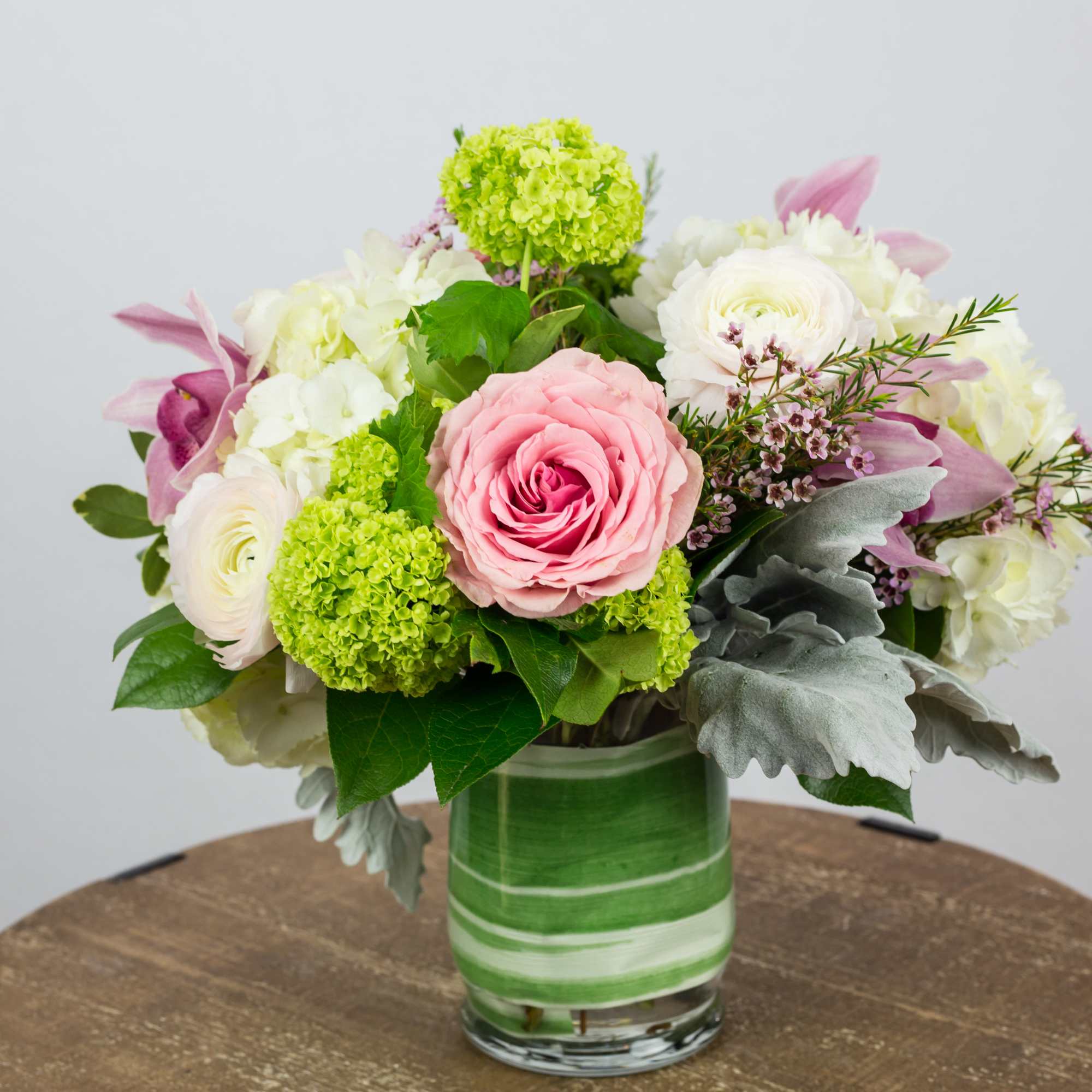 Hydrangea, green Viburnum, Roses, Green Phalaenopsis Orchids, Ranunculus, Waxflower, Dusty Miller. Flowers