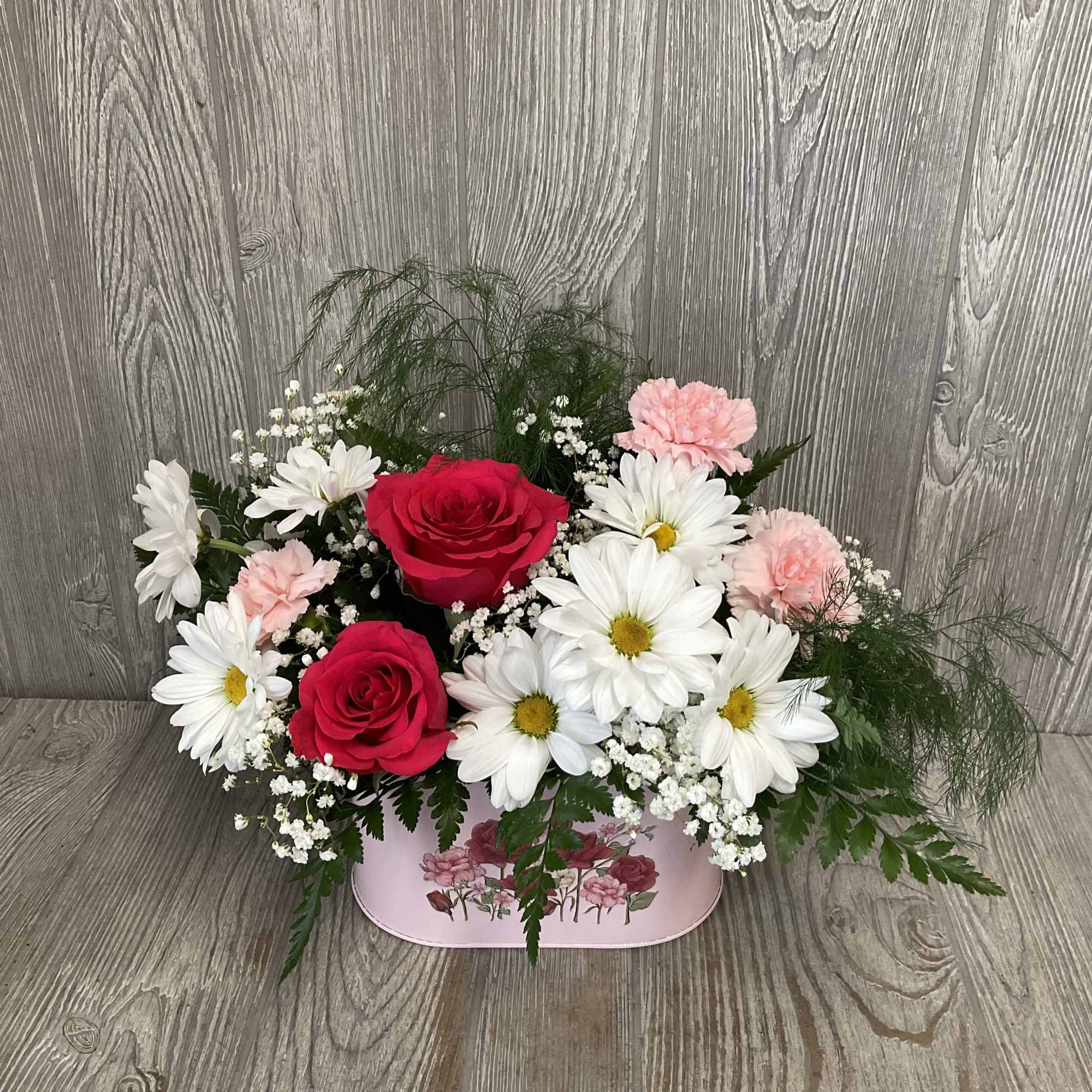 A beautiful bouquet of mixed flowers arranged in a keepsake metal planter