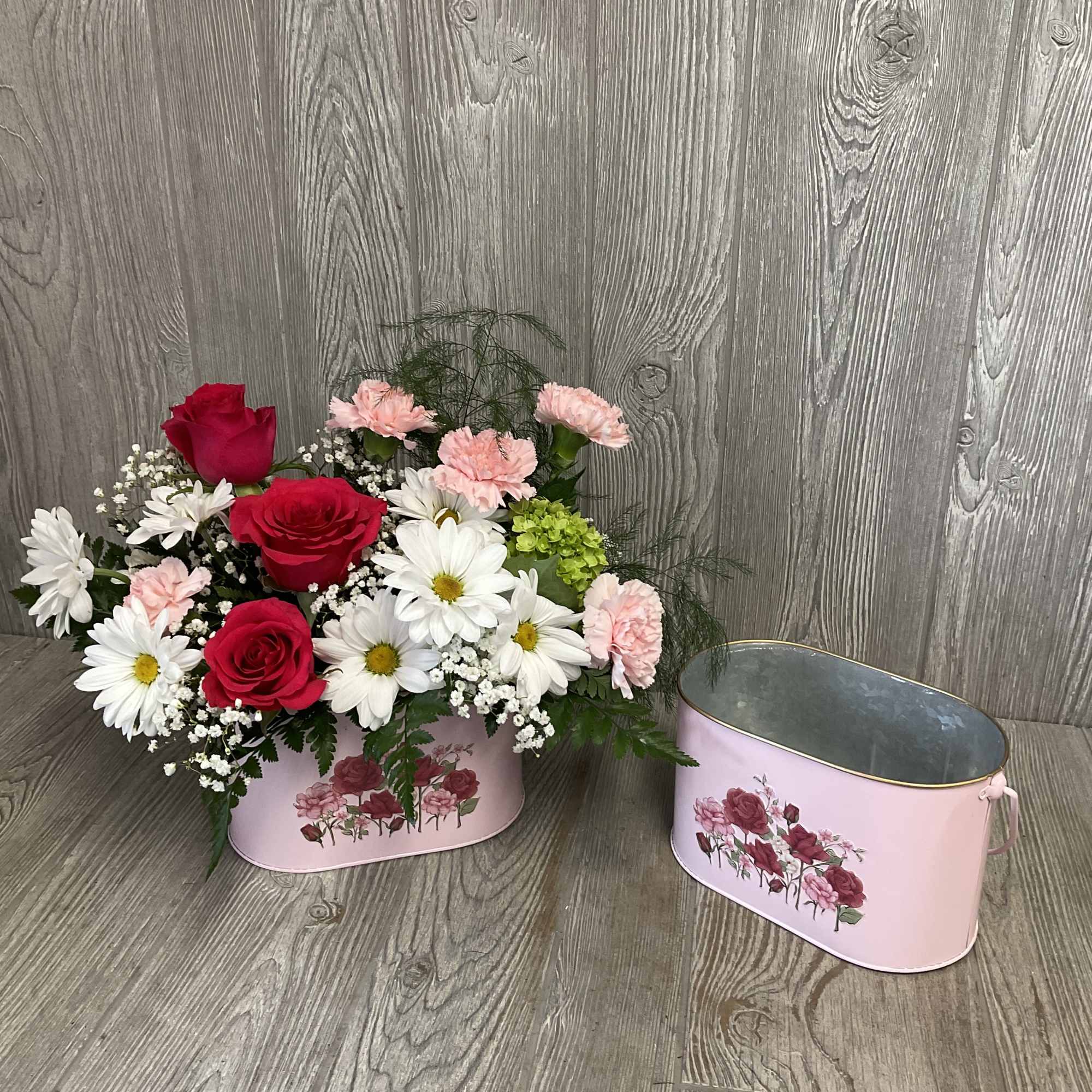 A beautiful bouquet of mixed flowers arranged in a keepsake metal planter