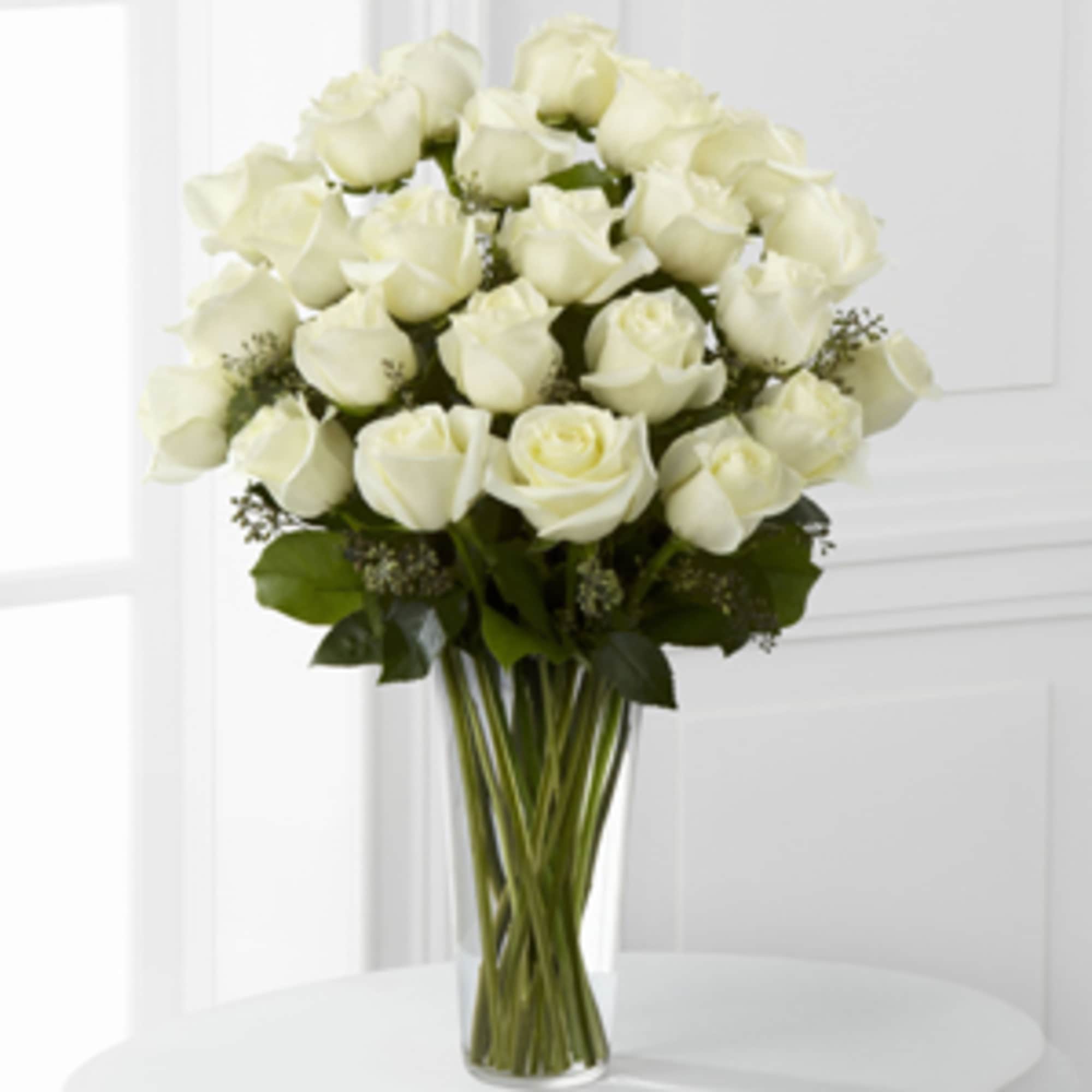 White roses are arranged in a sparkling glass vase, and accented with