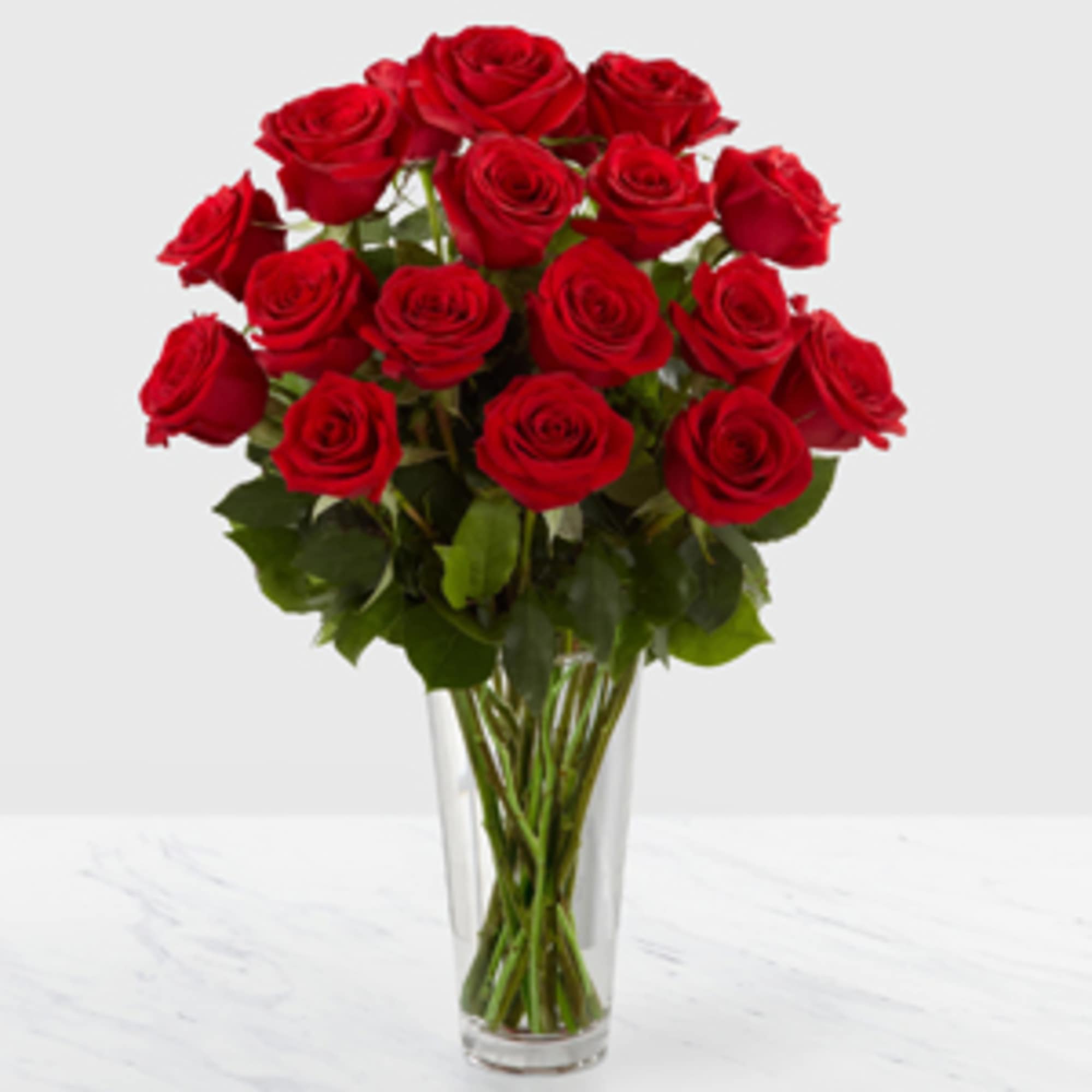 Romantic red roses are arranged in a sparkling glass vase, and accented