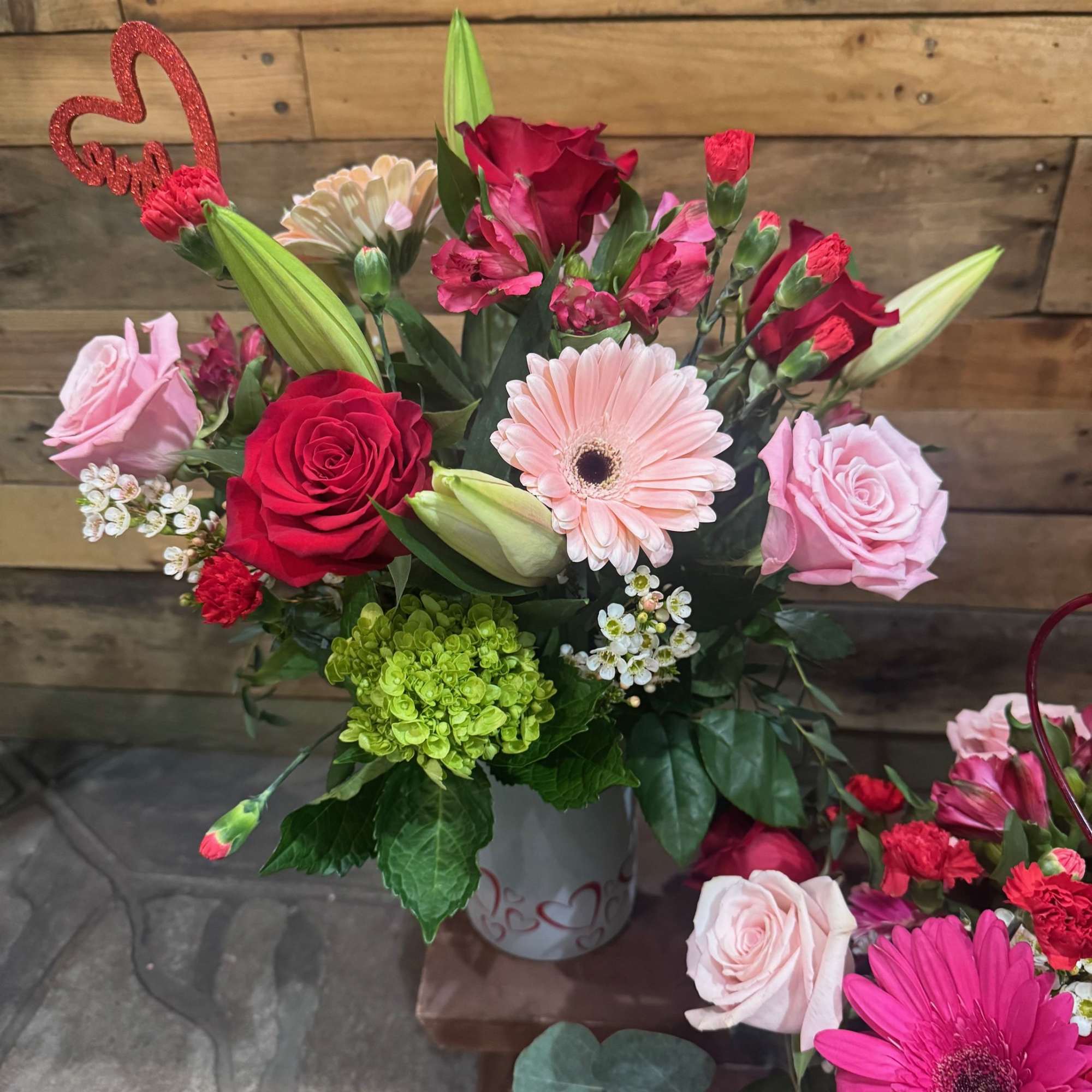 This arrangement contains different shades of pink roses and also red roses.