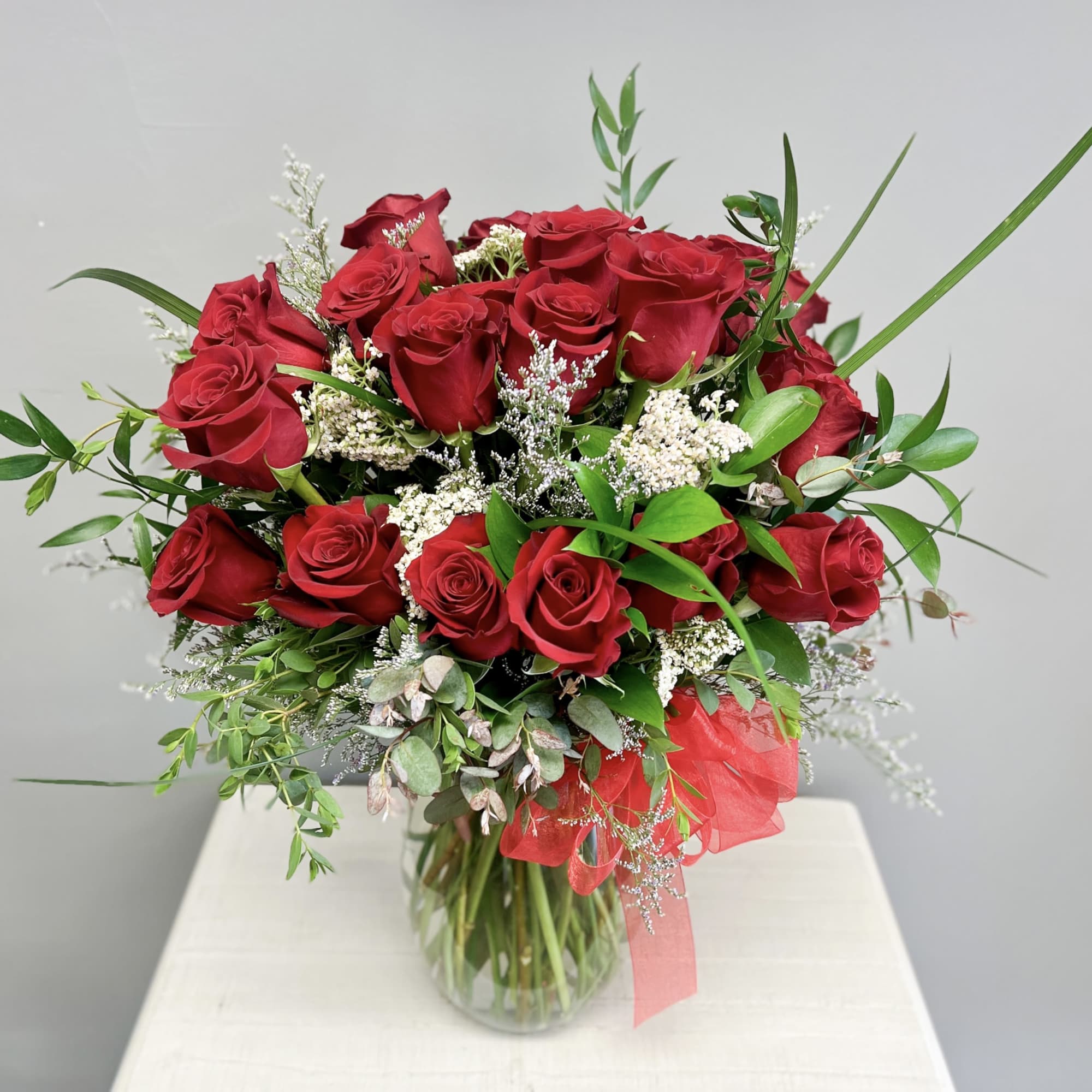 12 Red roses accented with premium greens in a  clear vase.