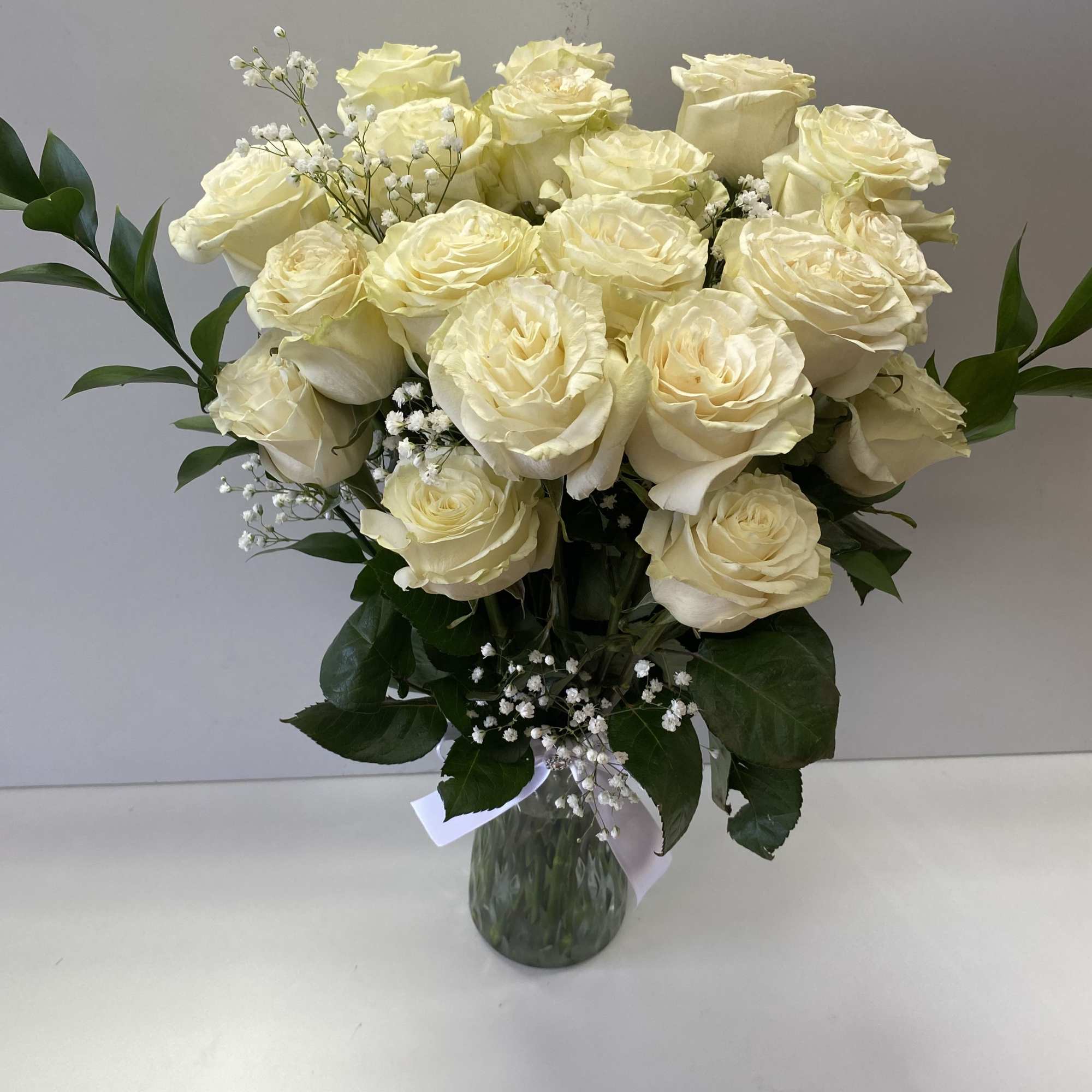 2 dozen of large white Roses in a vase ,harmoniously arranged, looking