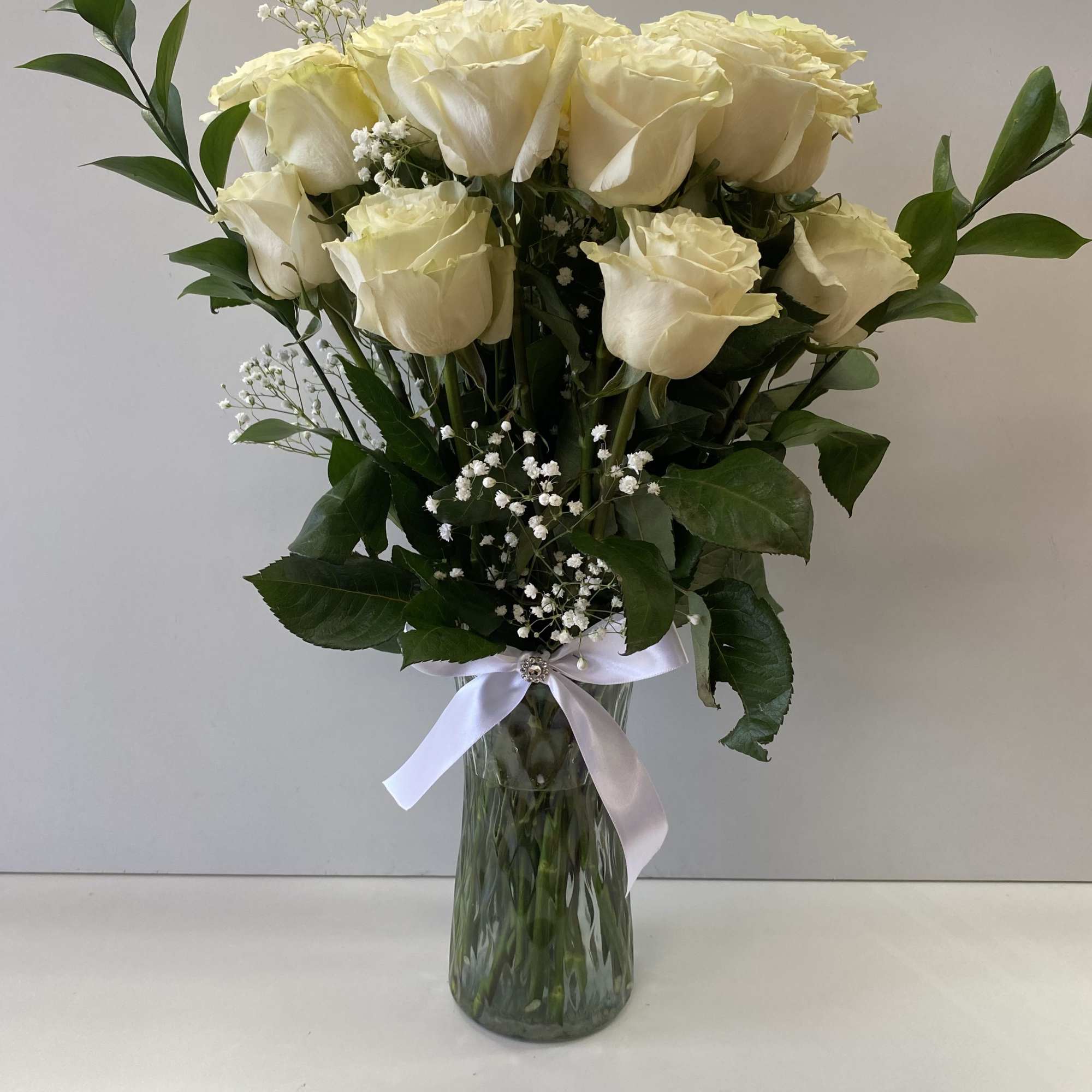 2 dozen of large white Roses in a vase ,harmoniously arranged, looking