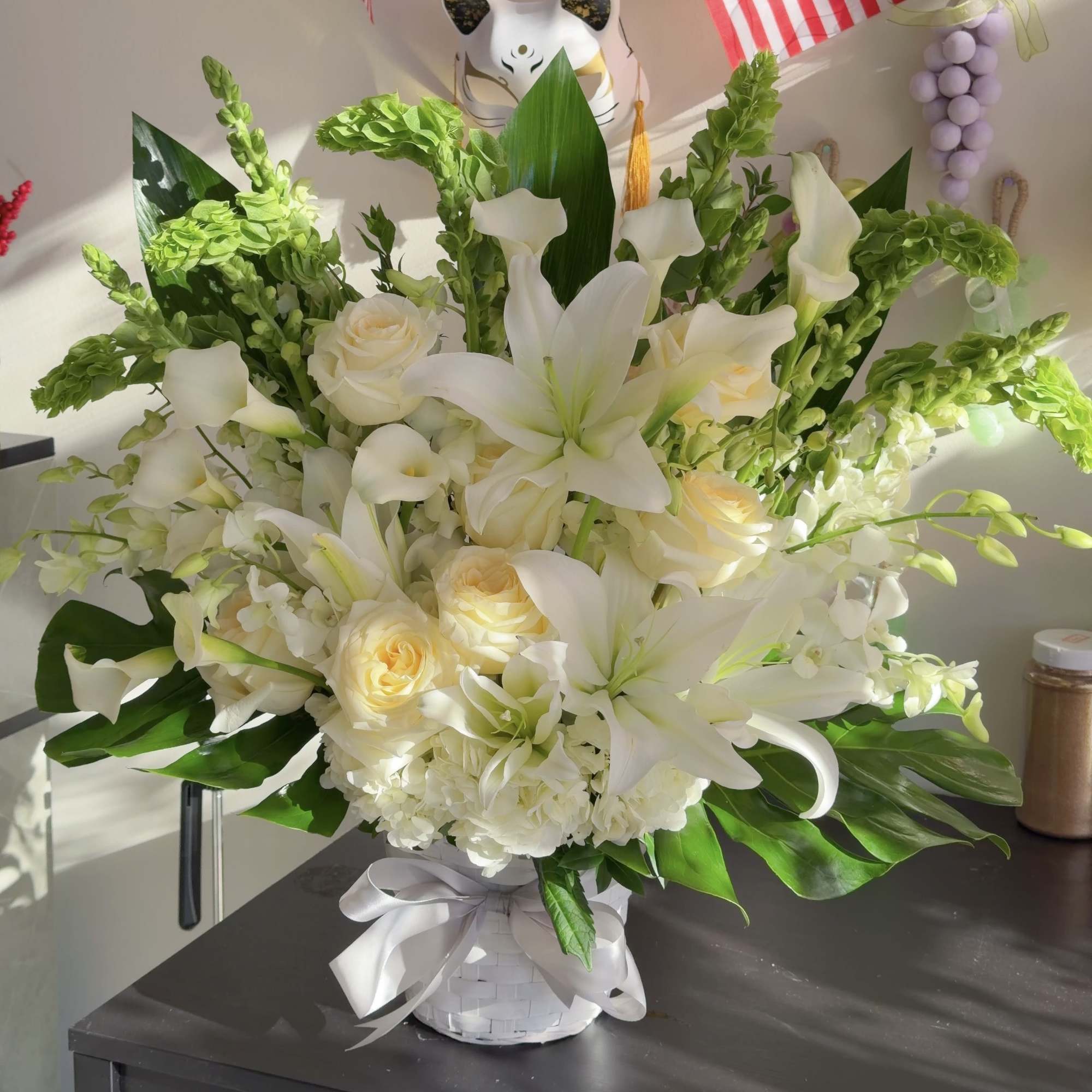 This elegant funeral arrangement is composed primarily of white lilies and white