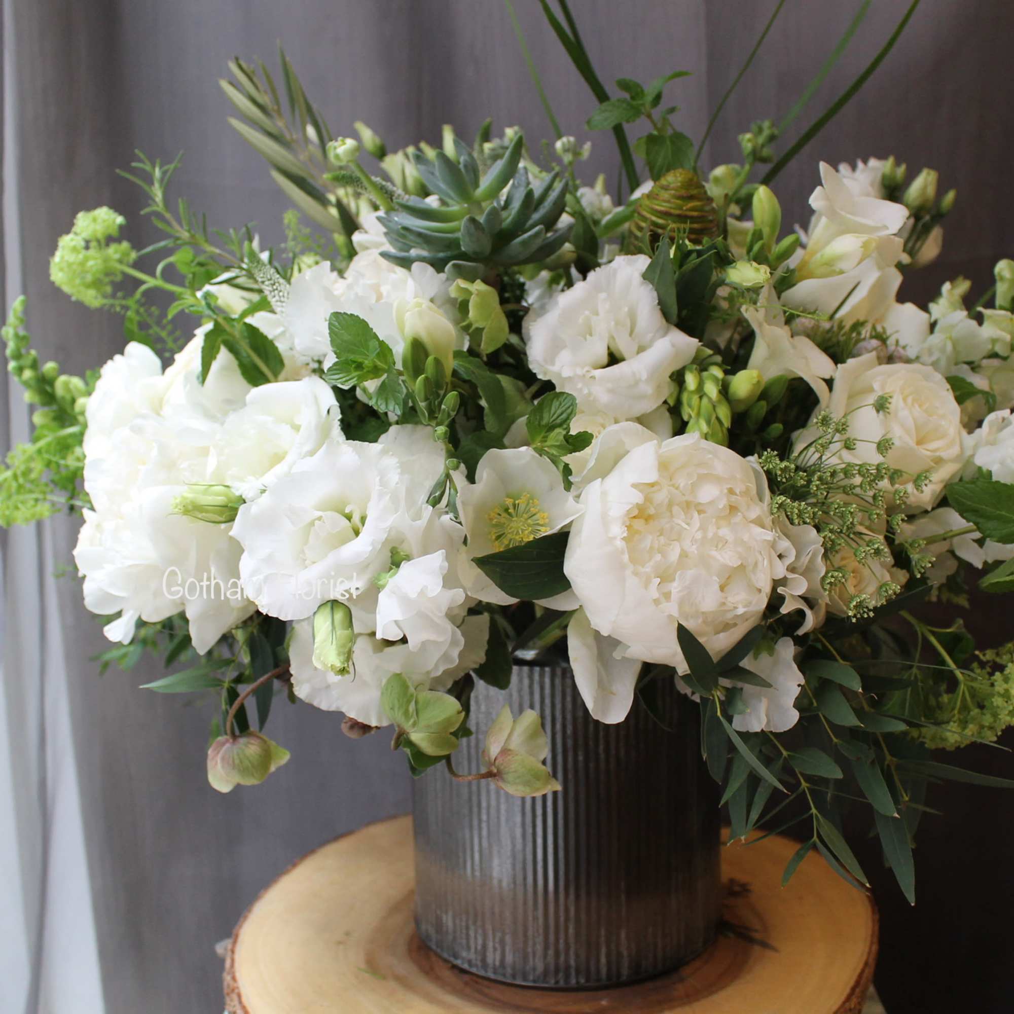 Tin vase filled with white seasonal flowers, lush greenery, succulents and herbs.