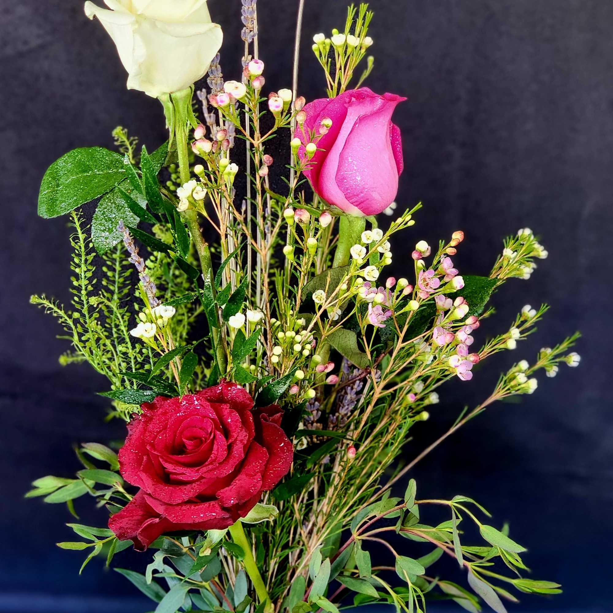 3 red roses in a bud vase with the citrus fragrance of