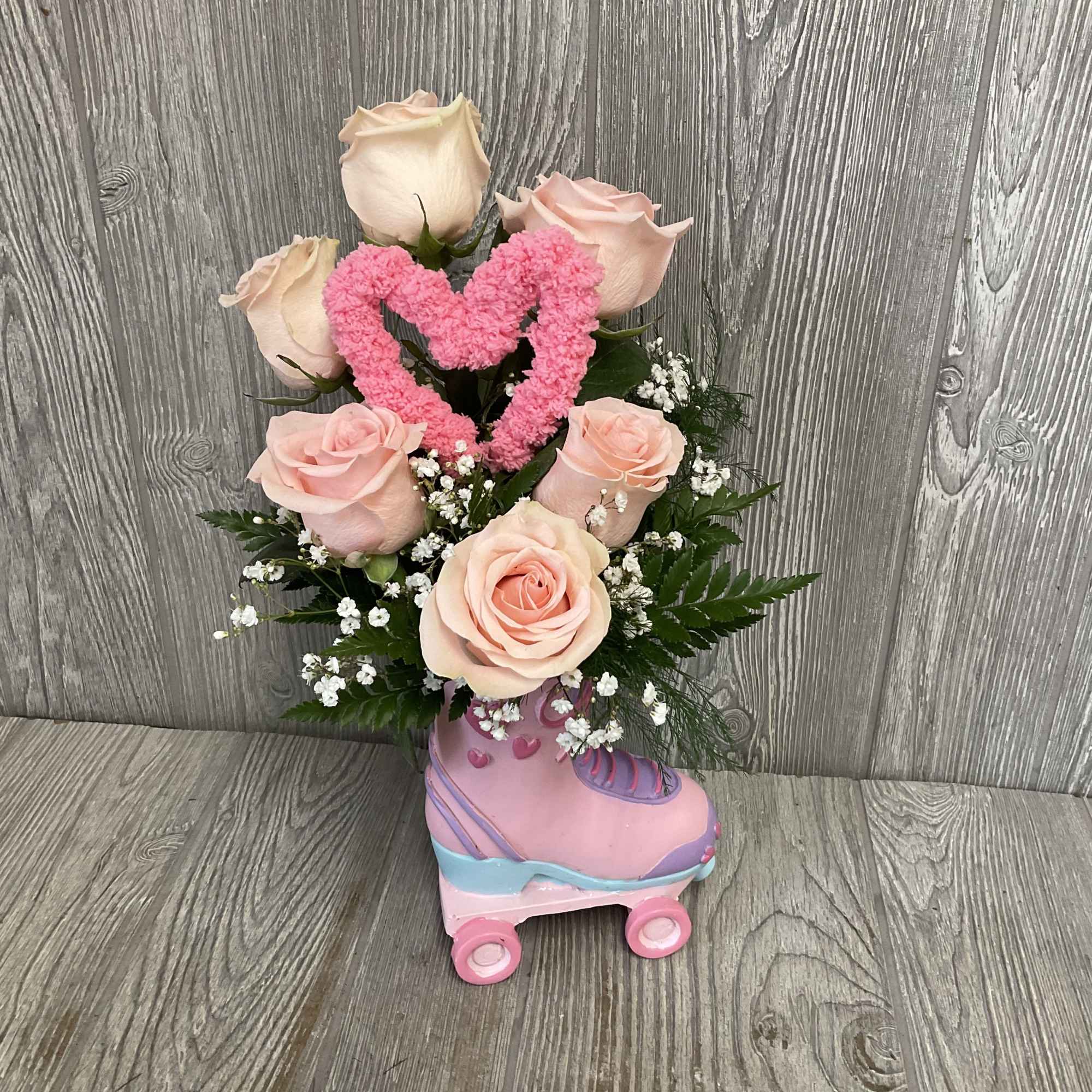 Beautiful light pink roses arranged in a keepsake ceramic roller skate container.