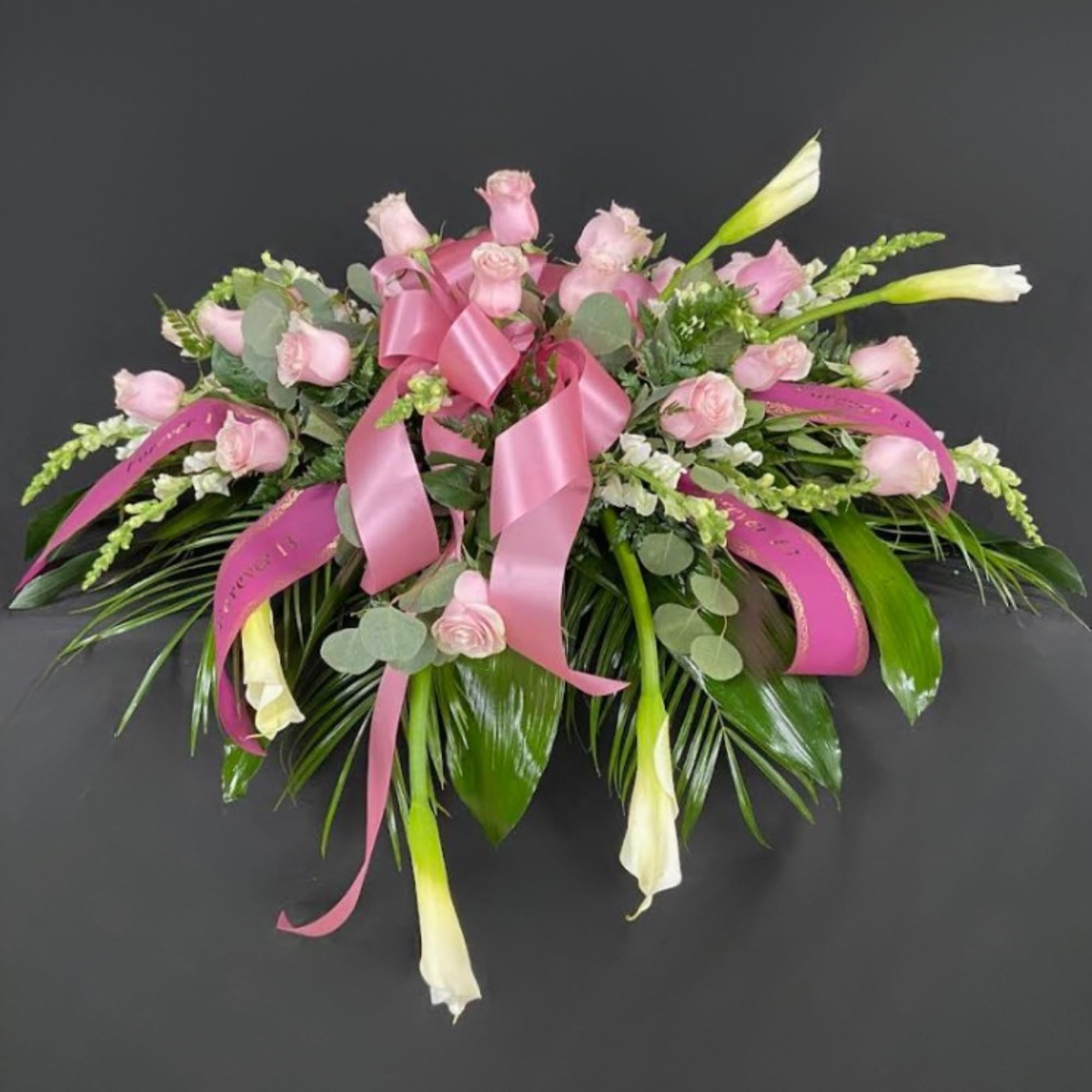 Full sized white calla lilies reach out of a bed of mixed