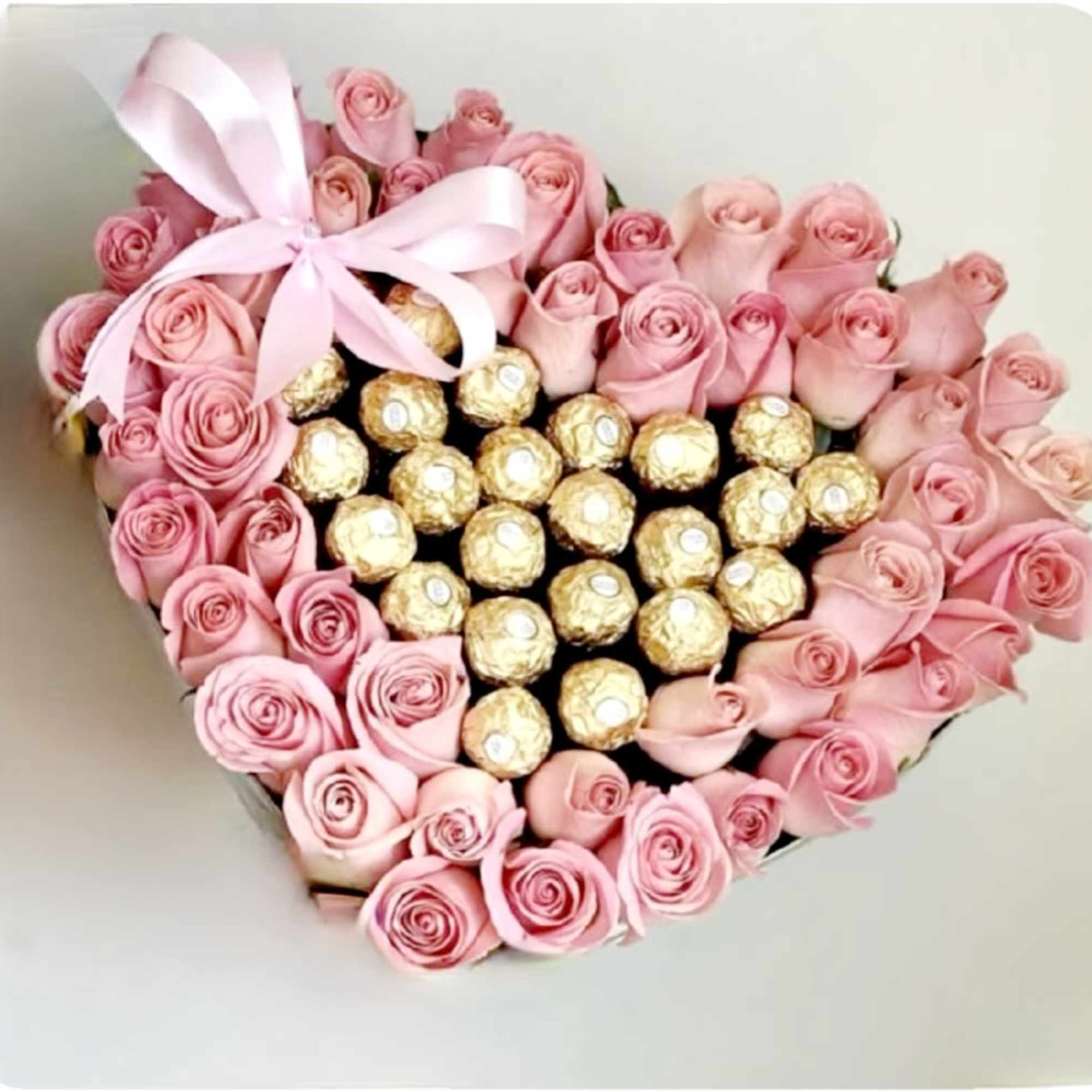 This heart-shaped arrangement features a border of neatly arranged pink roses encircling