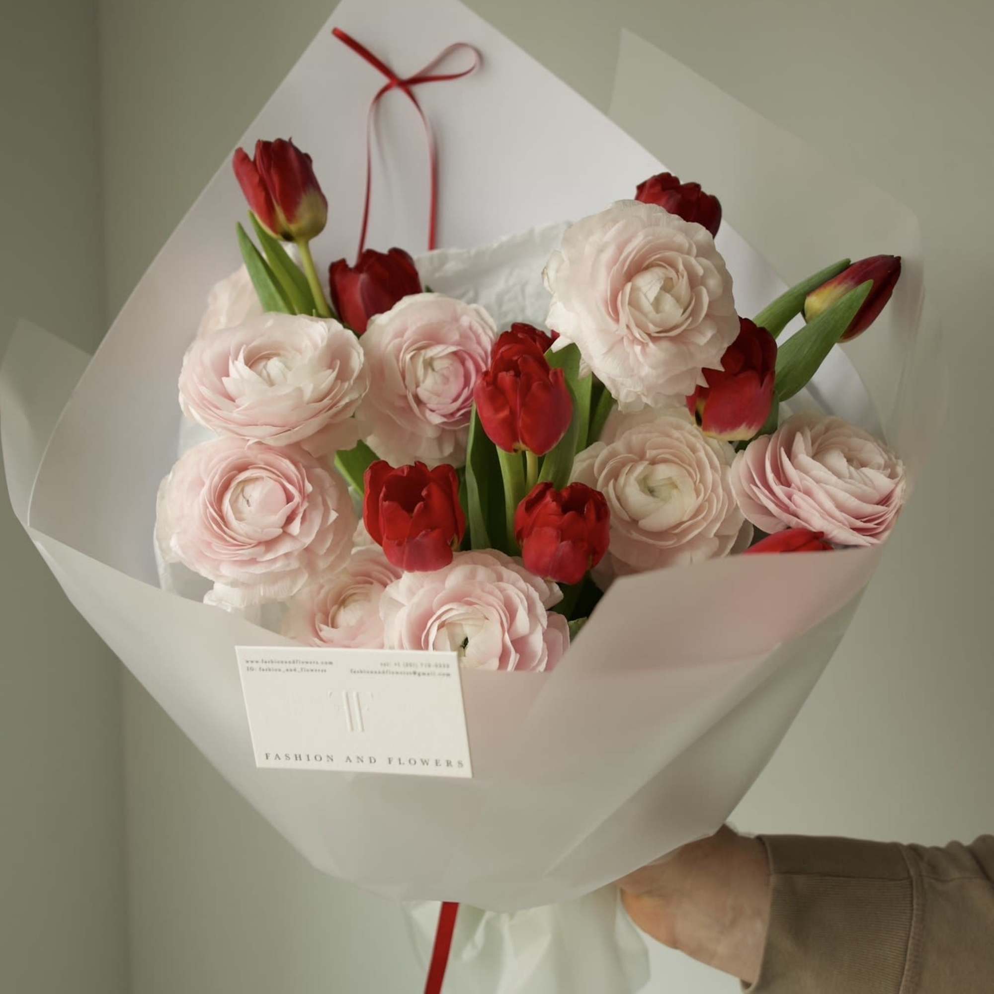 An elegant and romantic bouquet combining soft blush ranunculus with vibrant red