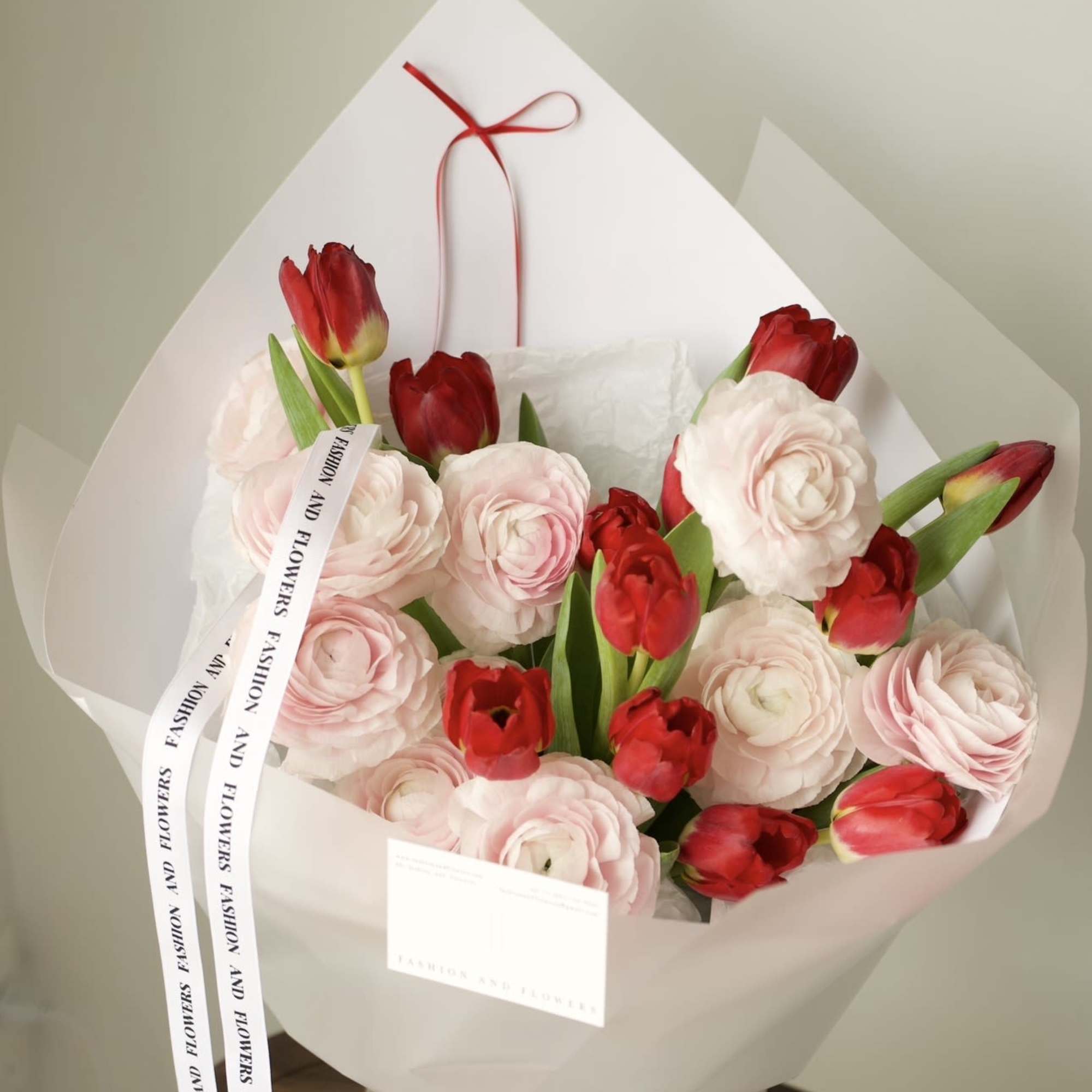 An elegant and romantic bouquet combining soft blush ranunculus with vibrant red