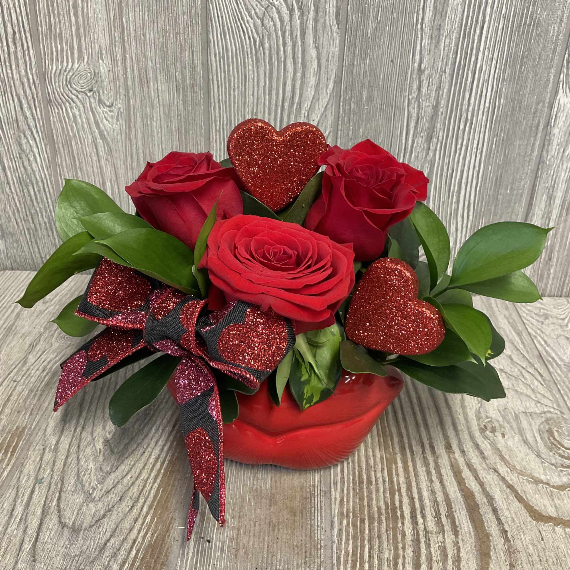 A modern elegant arrangement of red roses in a keepsake ceramic lips