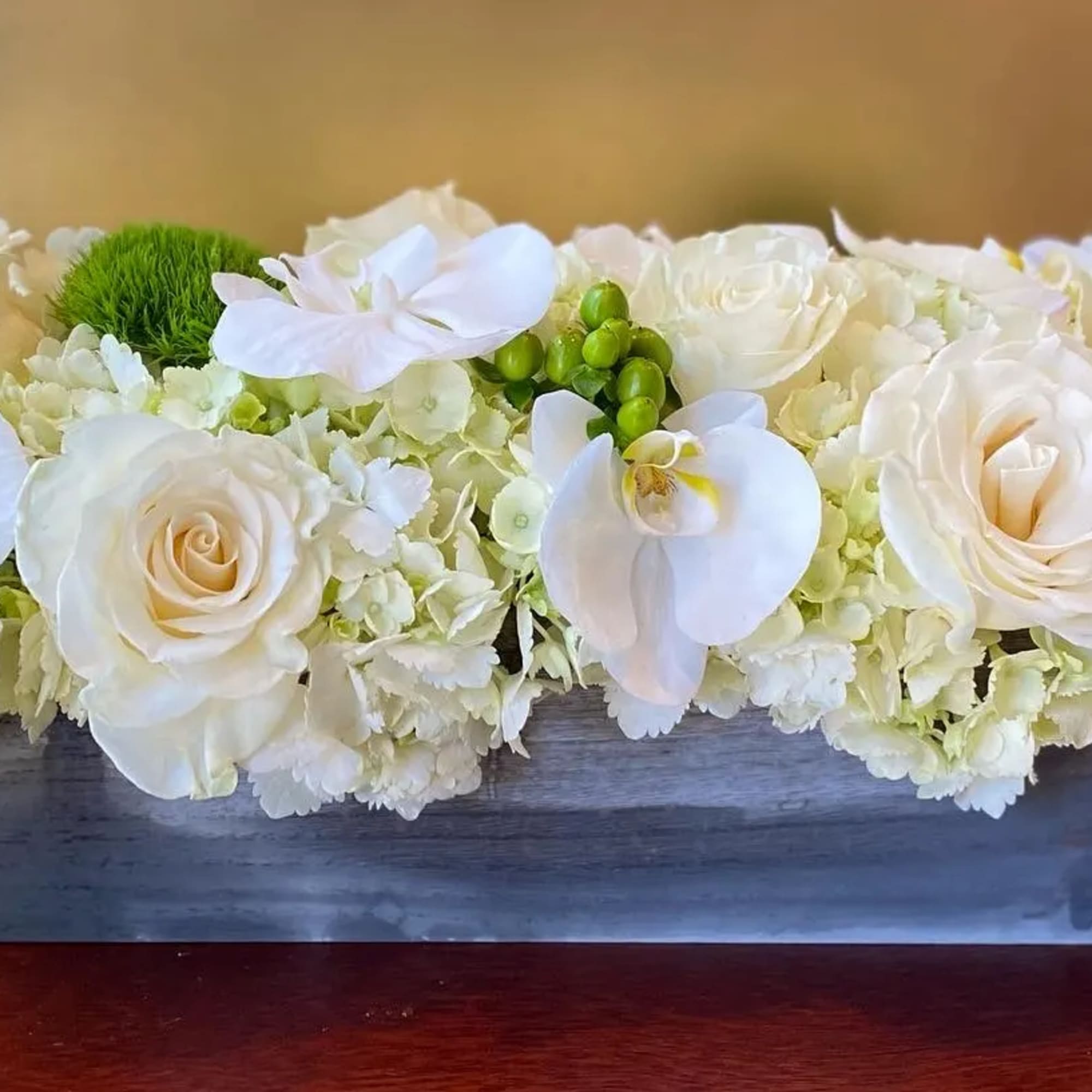 The Noir Chic Green Fusion arrangement features an assortment of white roses