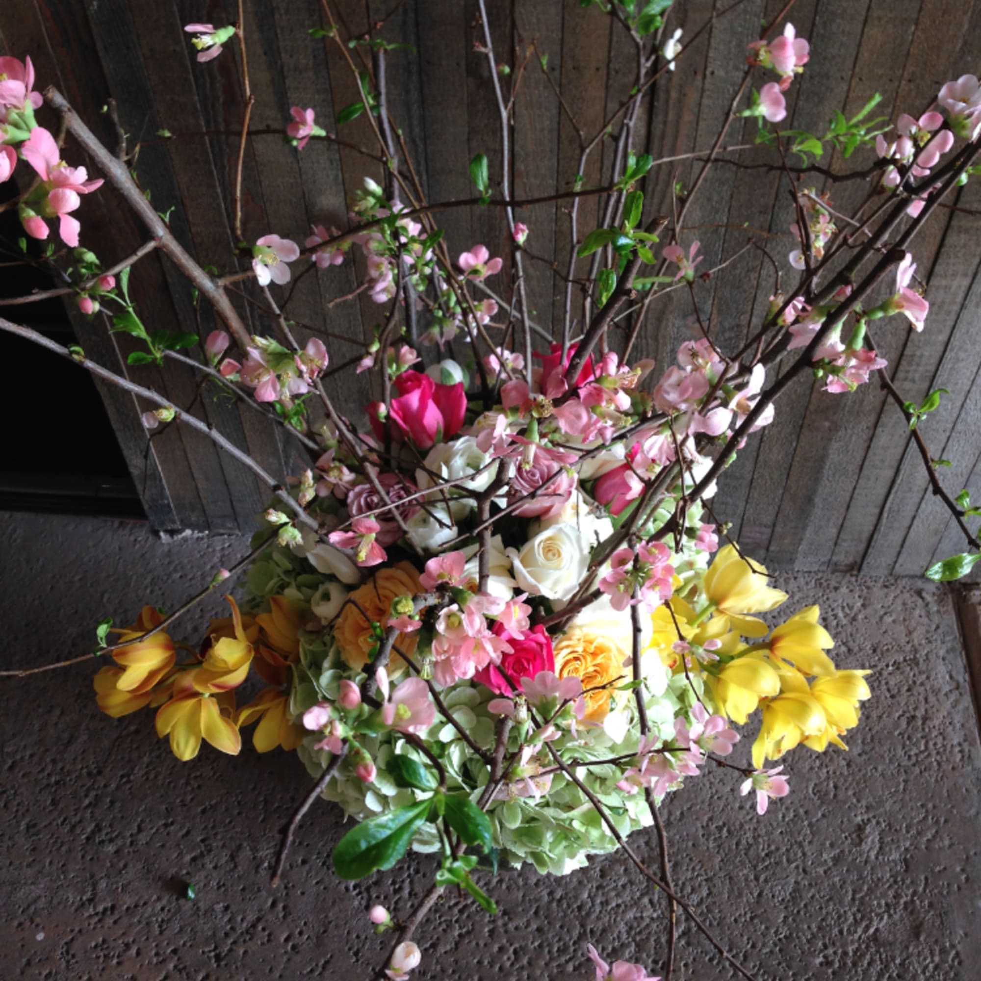 A mix of roses, hydrangeas, orchids and cherry blossoms in a tall