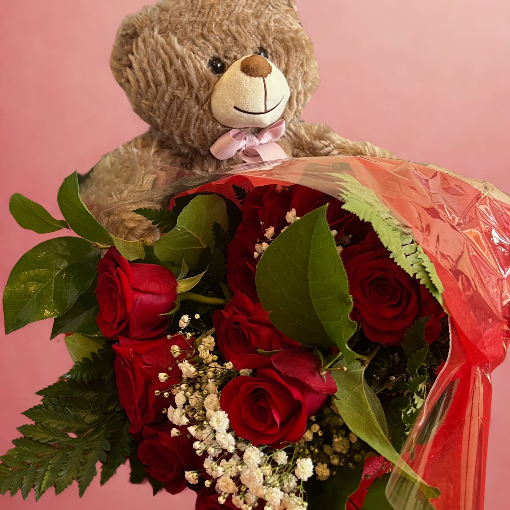 Wrapped roses paired with a cuddly teddy bear create a classic, heartwarming