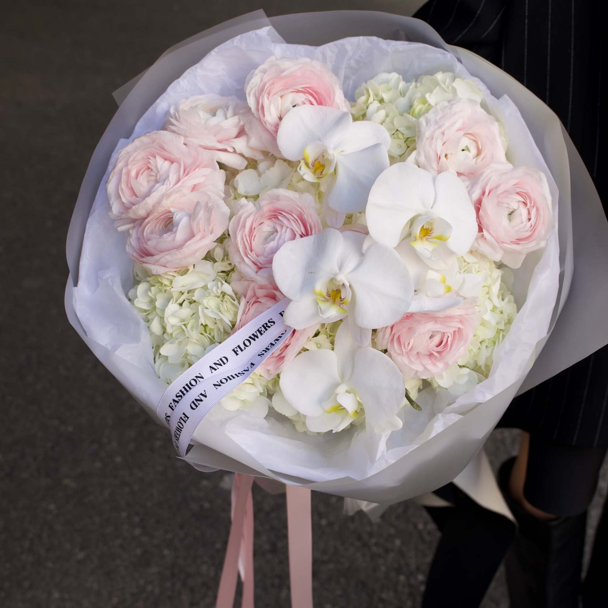 An airy couture-style bouquet featuring blush ranunculus, white phalaenopsis orchids, and soft