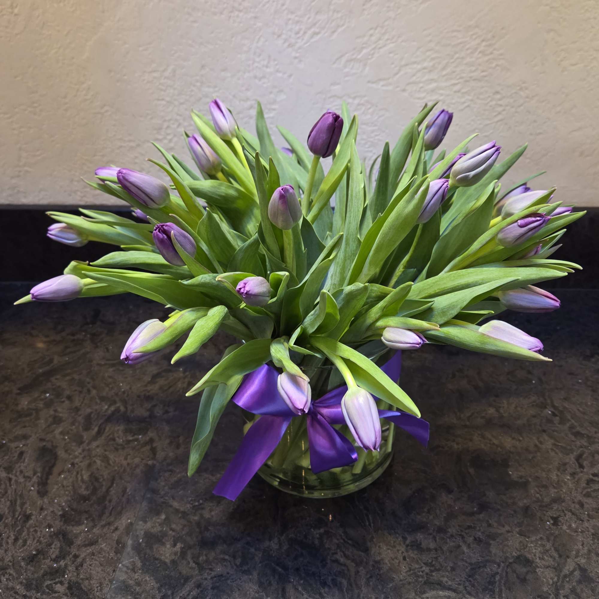 50 stunning tulips in a leaf wrapped glass vase.
Please specify your desired
