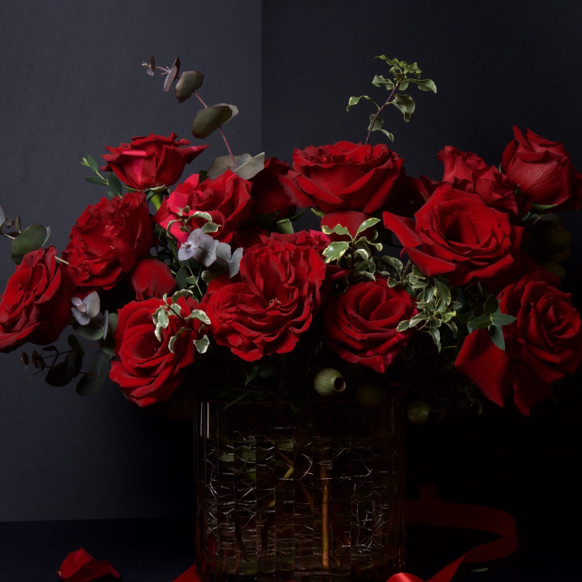 This striking arrangement showcases lush red roses arranged in a full, elegant