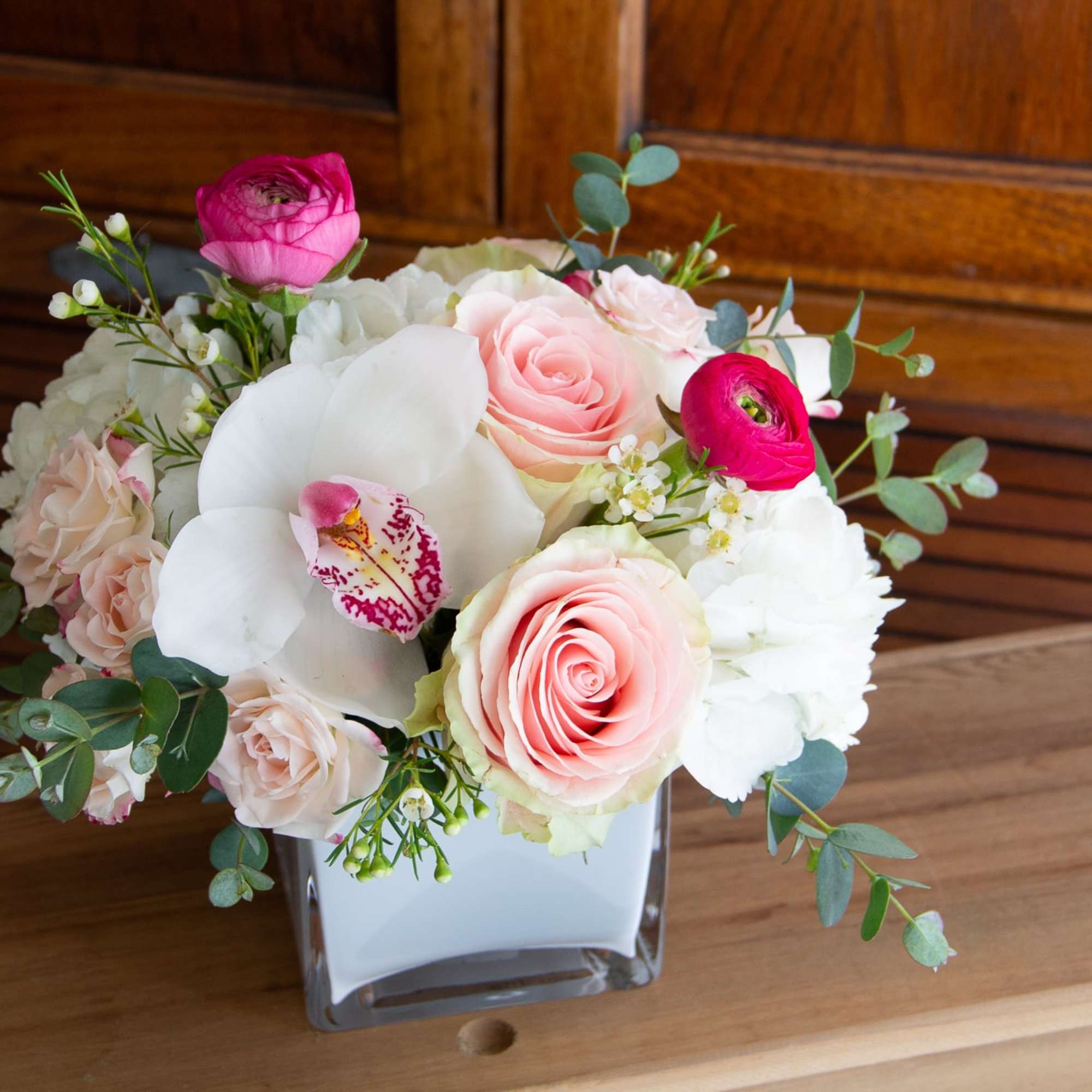 A compact, more modern style arrangement featuring roses, spray roses, hydrangea, and