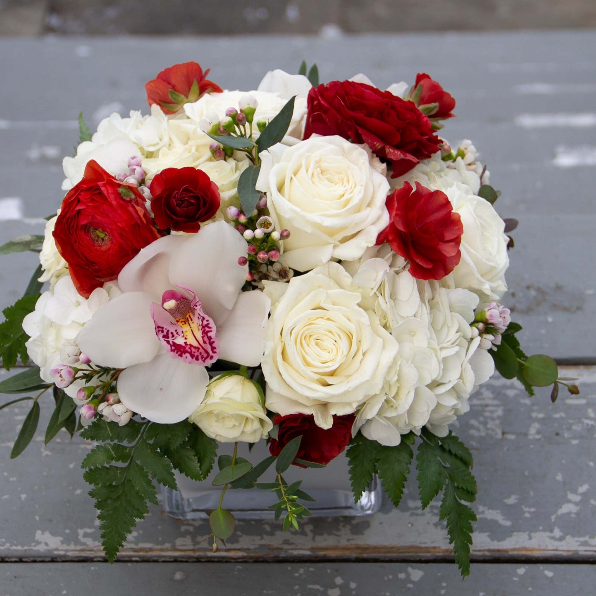 A compact, more modern style arrangement featuring roses, spray roses, hydrangea, and