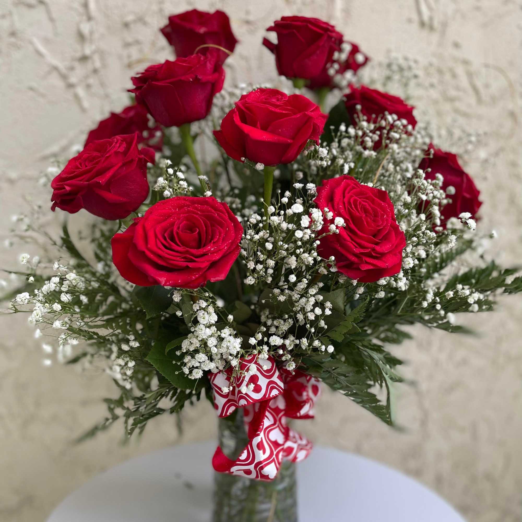 Gorgeous red blooms accented with baby&rsquo;s breaths and greens. 
Vase style will