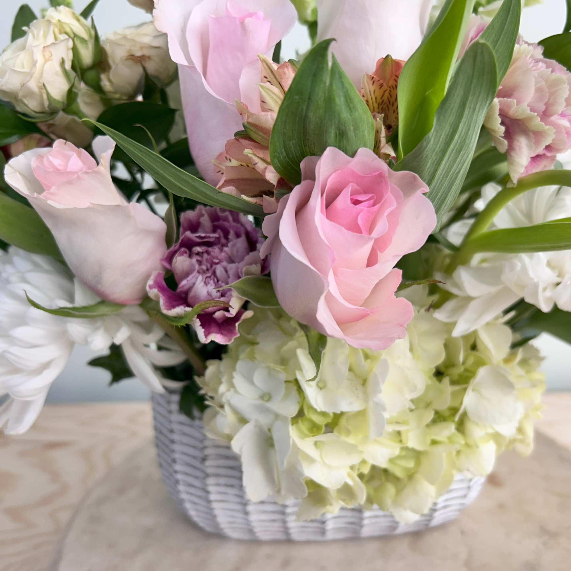 A lovely ceramic basket with flowers. Roses, tulips, hyacinth, and other filler