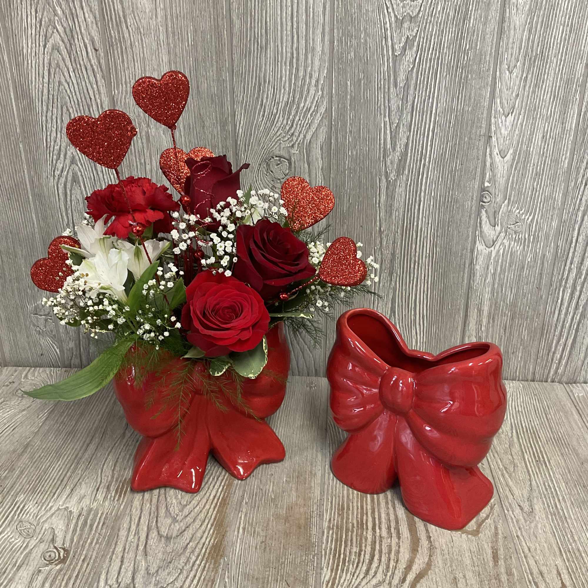 Fresh cute flowers arranged in a keepsake ceramic red bow vase. Flowers