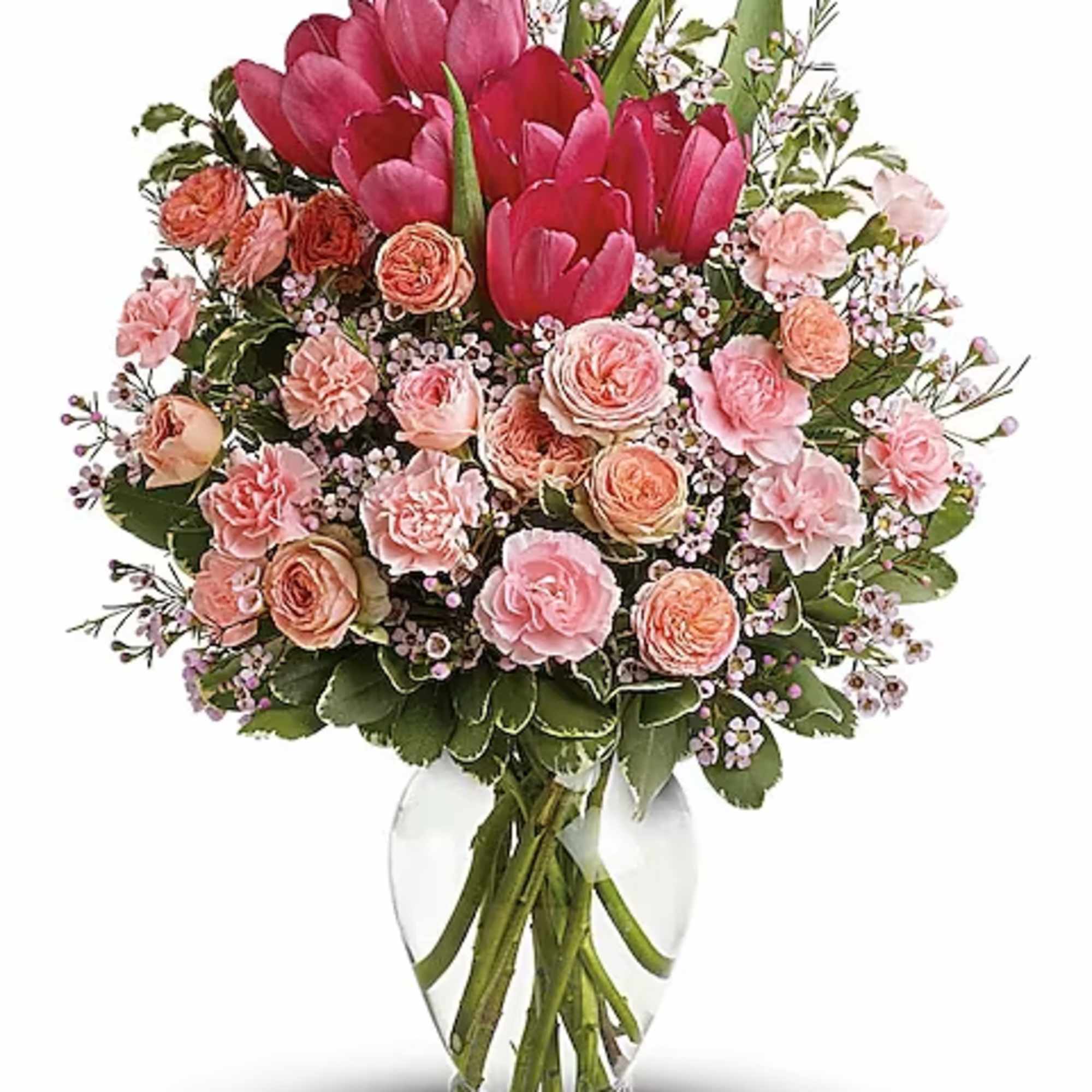 Spring into pink! Delicate roses, tulips and carnations fill a graceful vase