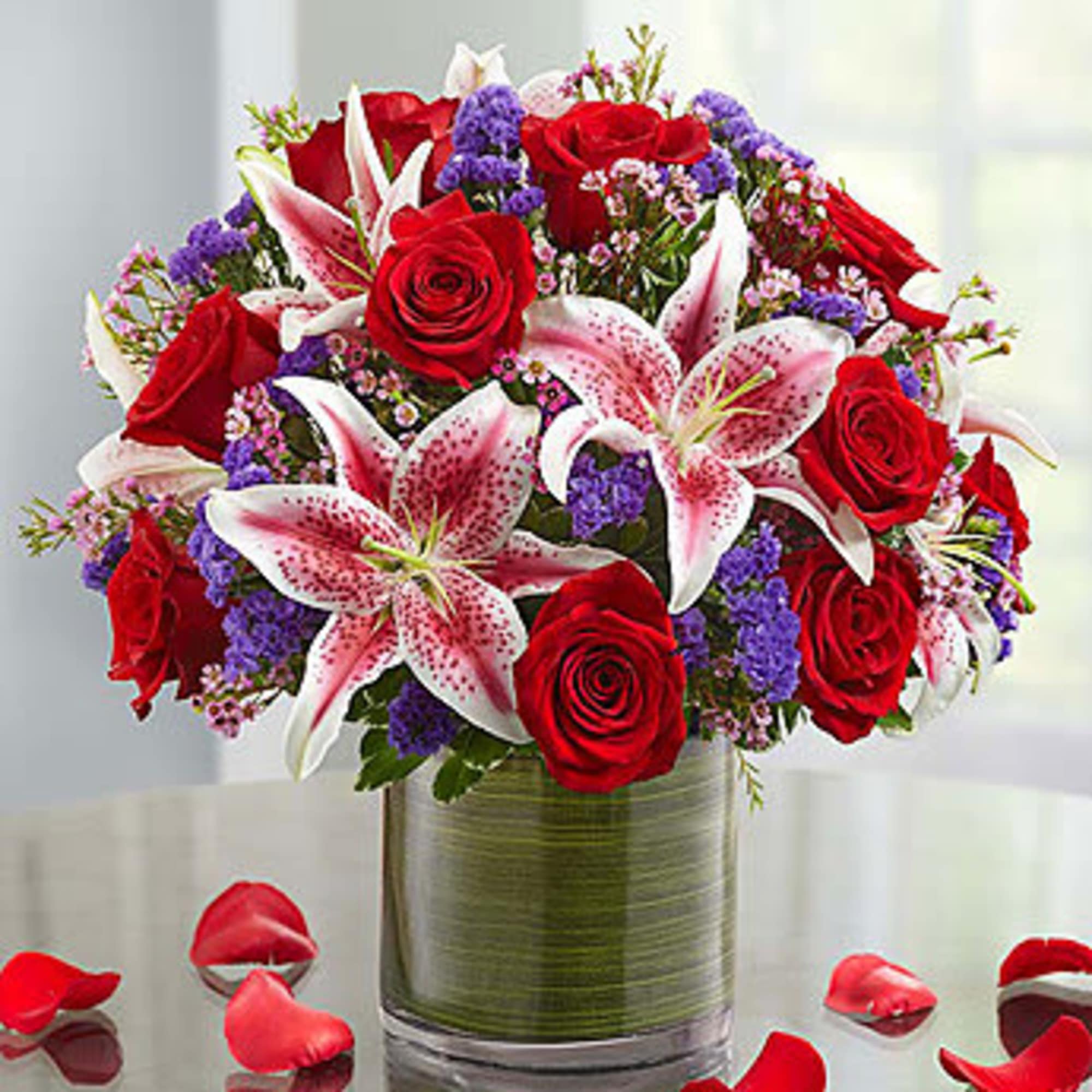 roses, lilies wax flowers and staice  arrange in the cylinder vase