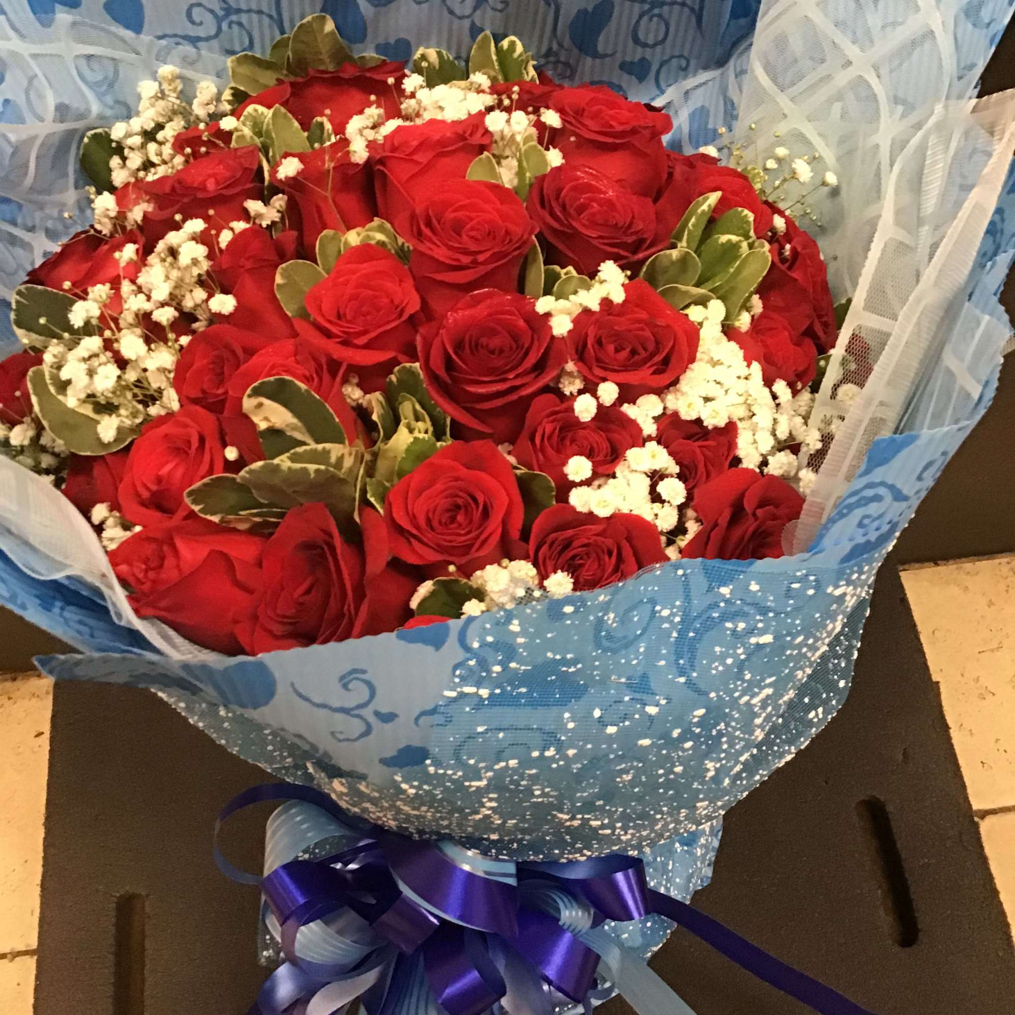 3 Dozen red roses with baby's breath wrapping in a blue craft