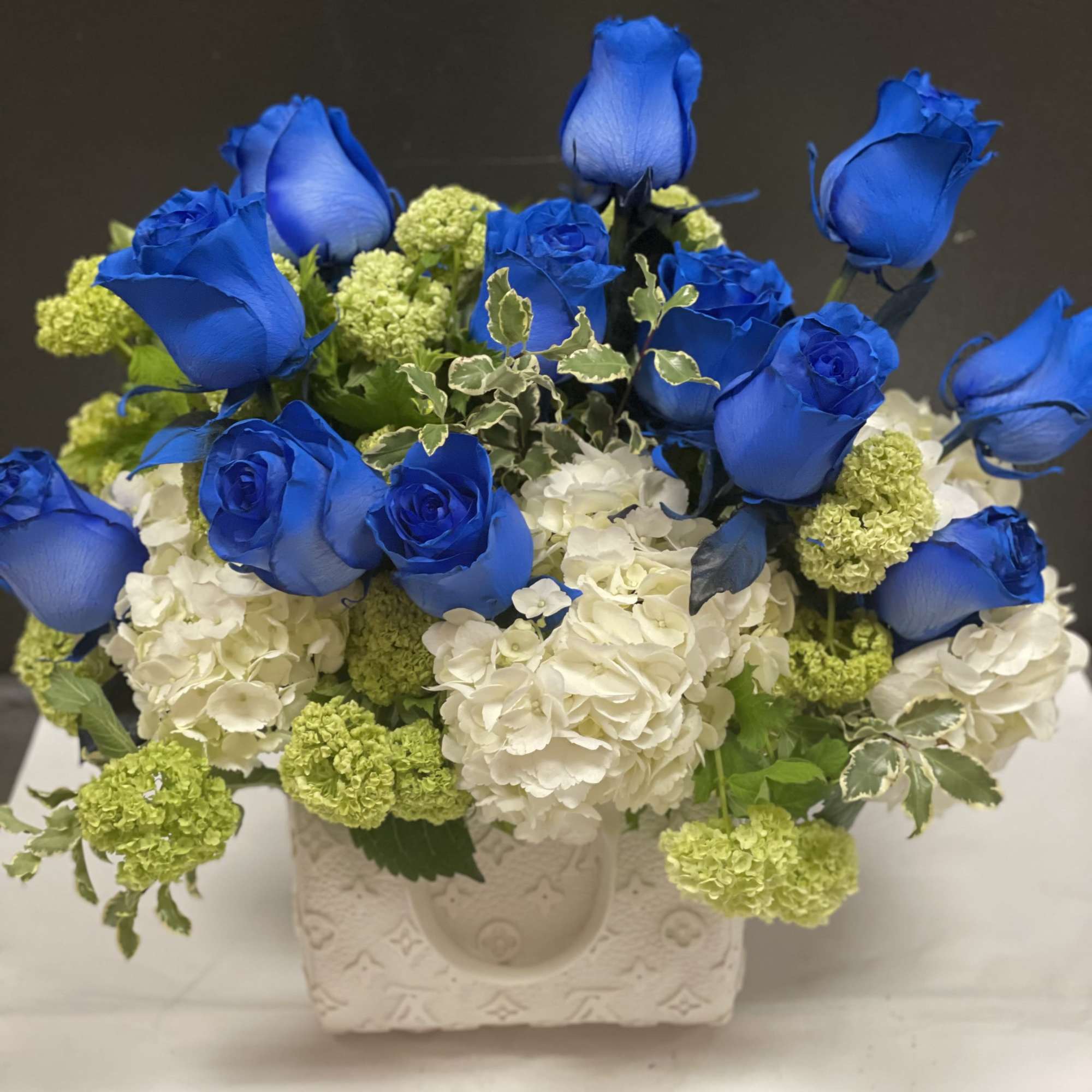 This beautiful arrangement made with blue roses , white and white hydrangea