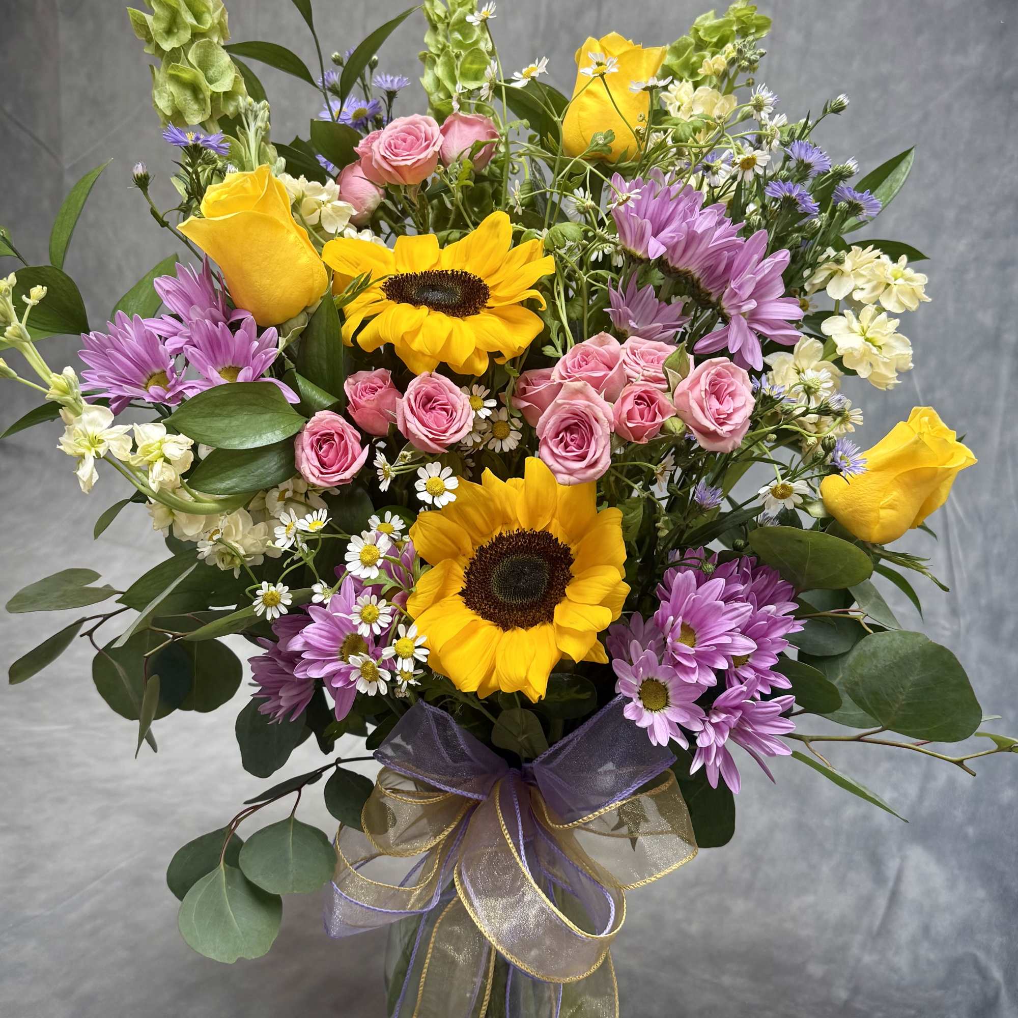 A radiant mix of golden sunflowers, sunny yellow roses, delicate pink spray
