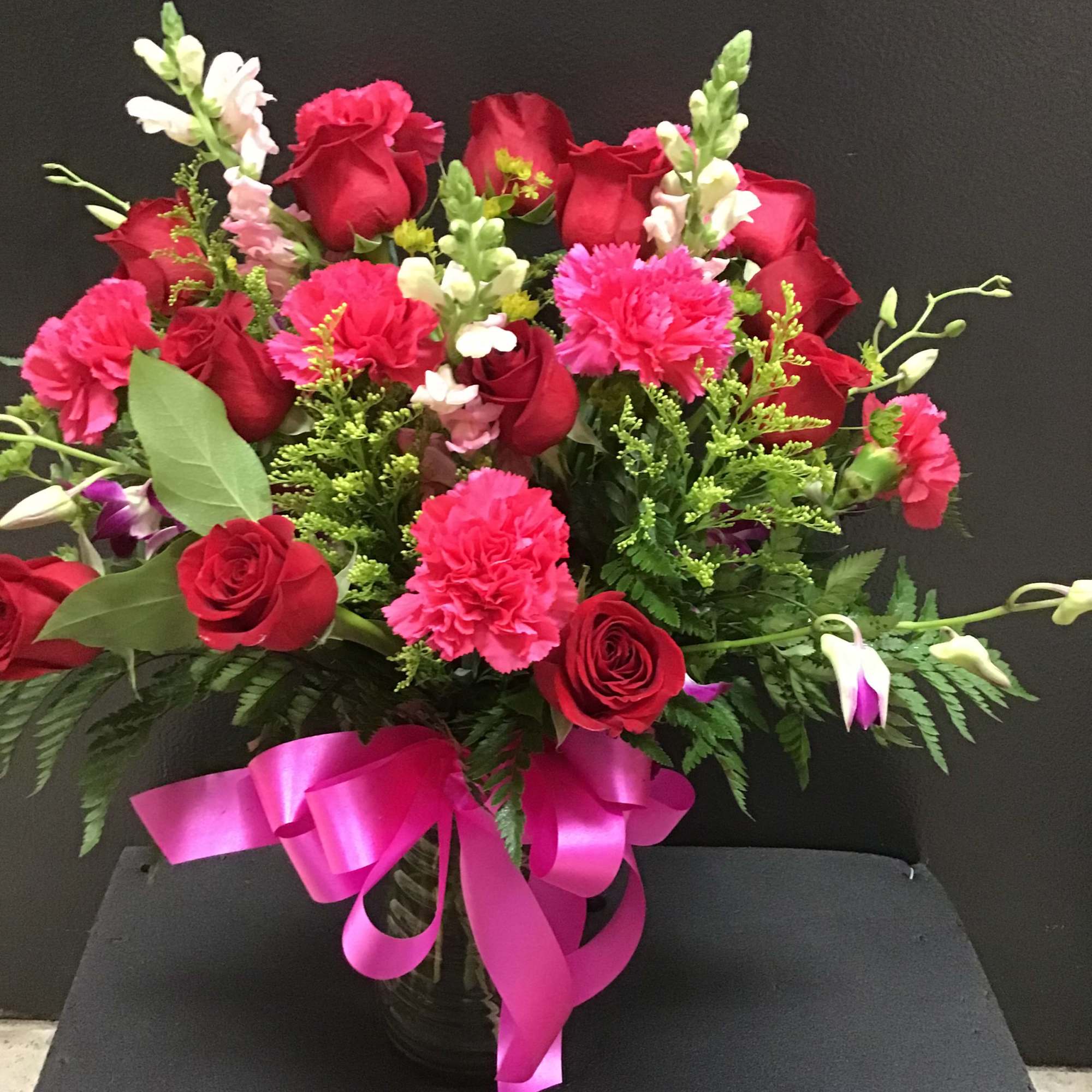 This beautiful arrangement make with red roses, hot pink carnations,  purple