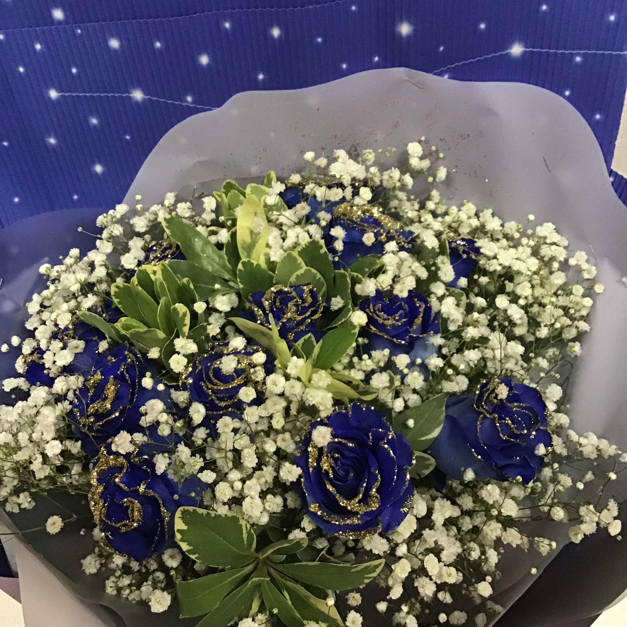 A dozen blue roses with gold glitter on the petal , wrapping