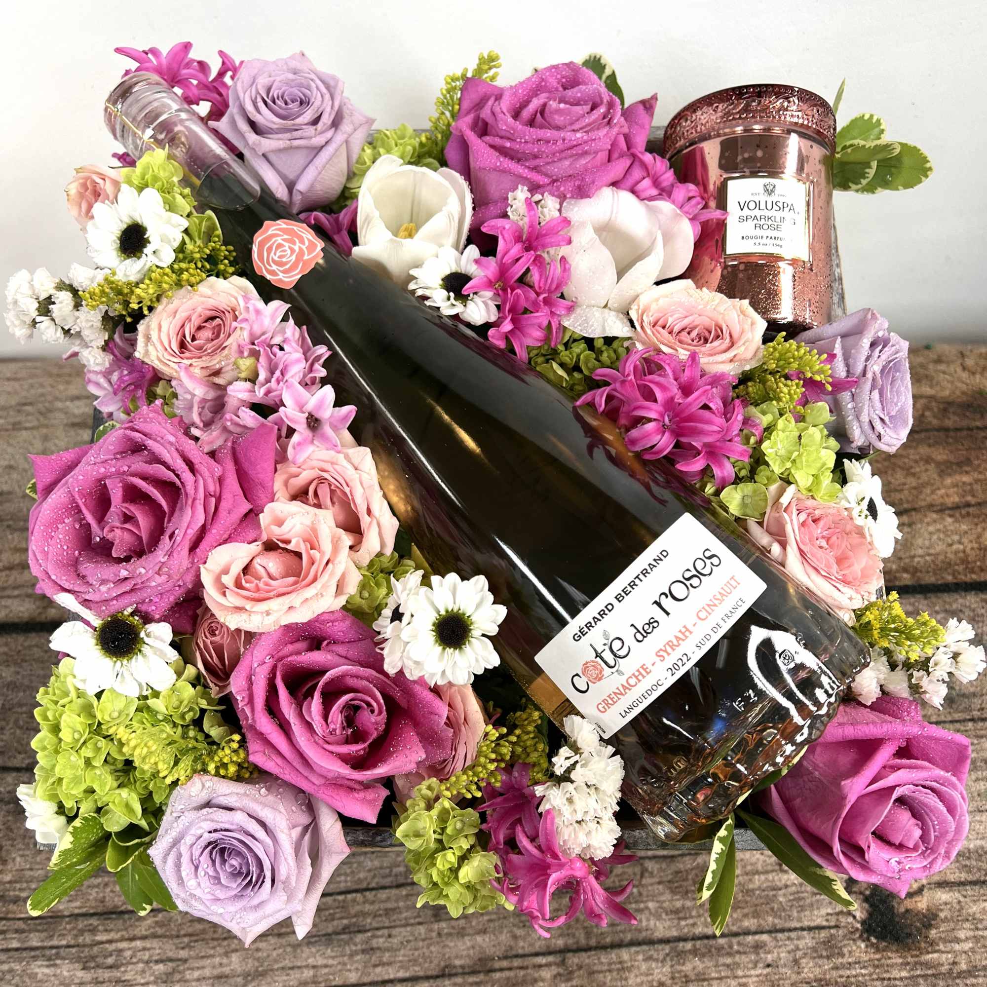 A bottle of Ros&egrave; placed on a bed of flowers accompanied by
