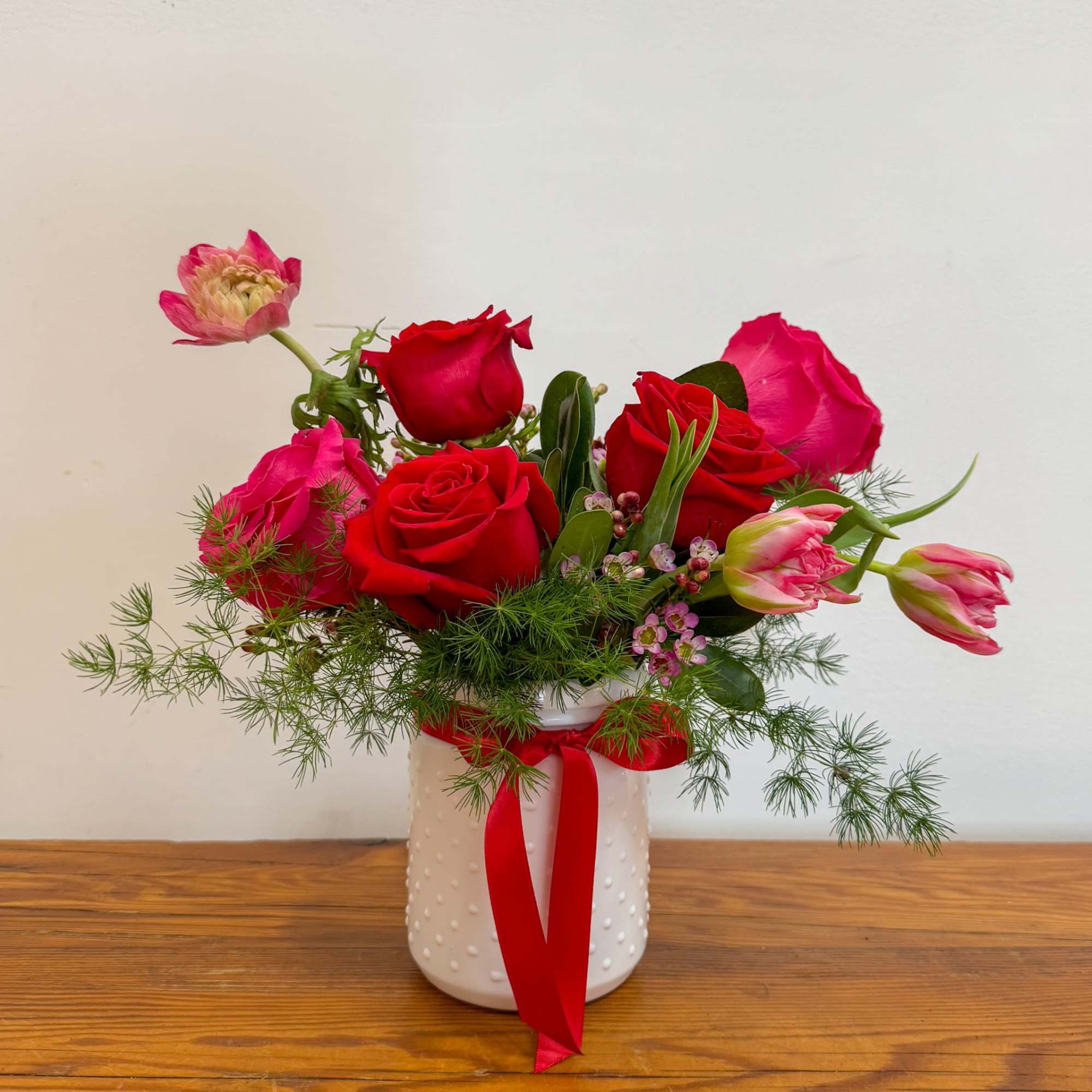A classic red arrangement with red roses, tulips, and ranunculus in a