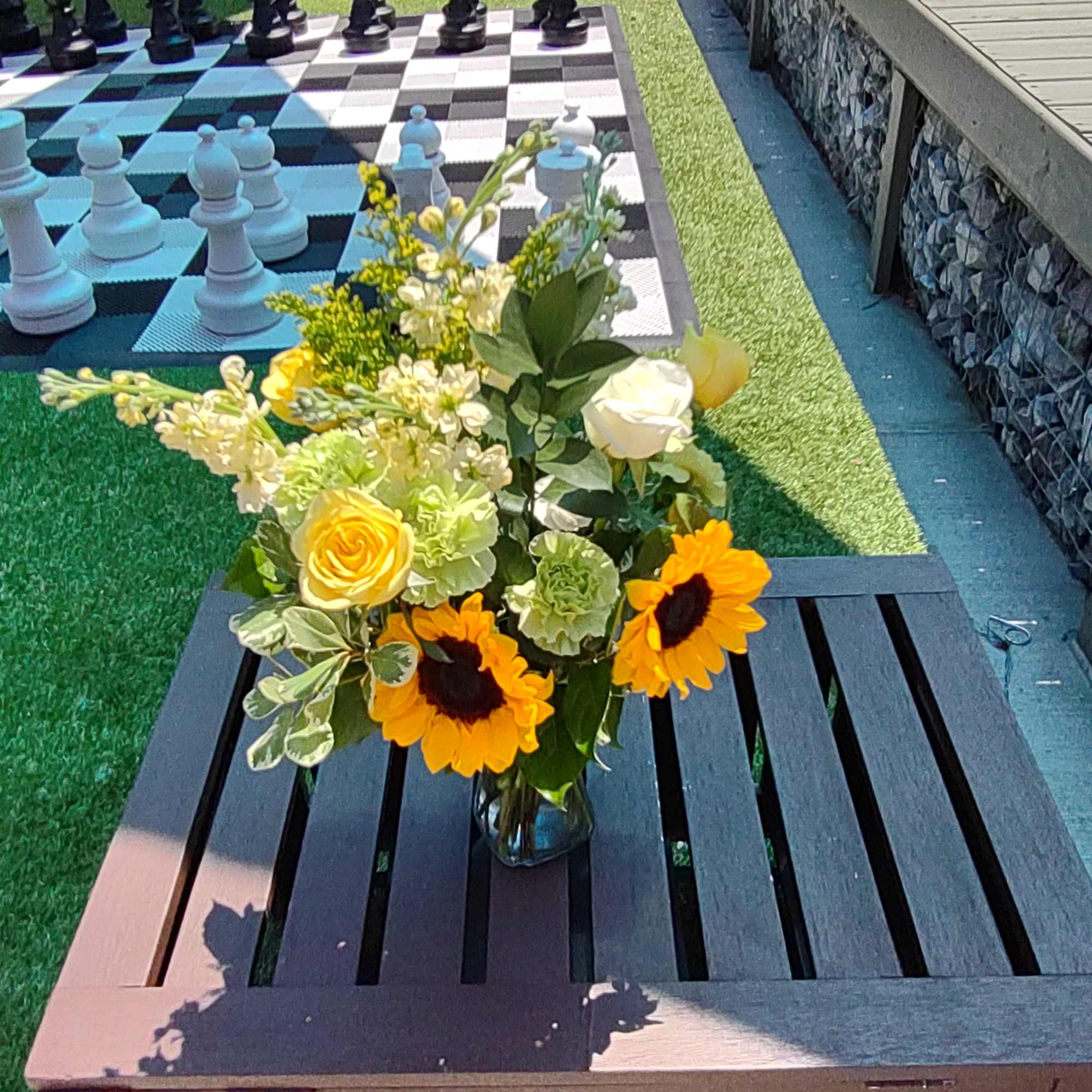 A summery blend of white stock, Sunflowers, Roses and Carnations with assorted