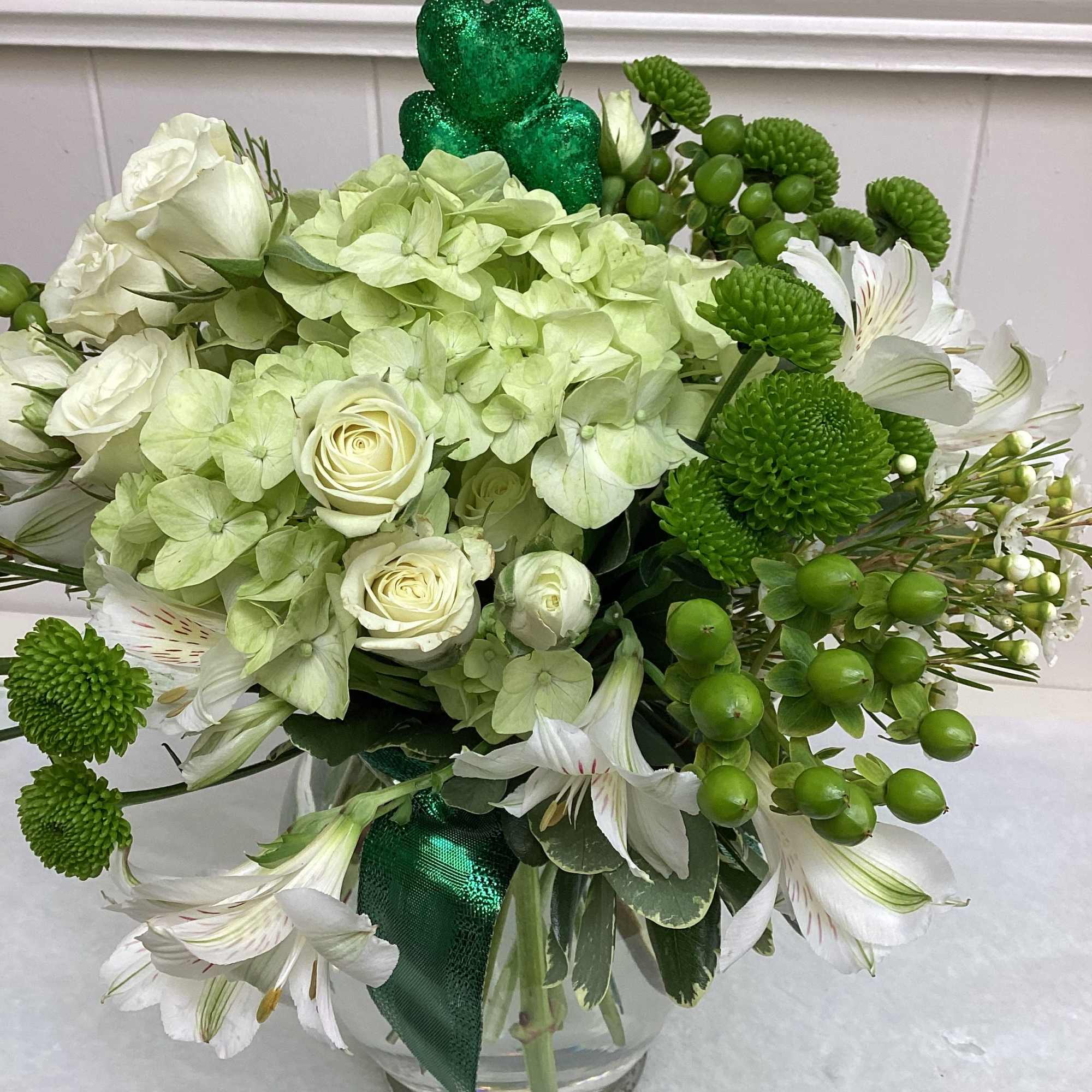 This lusciouss arrangement features green and white flowers. White spray roses complement