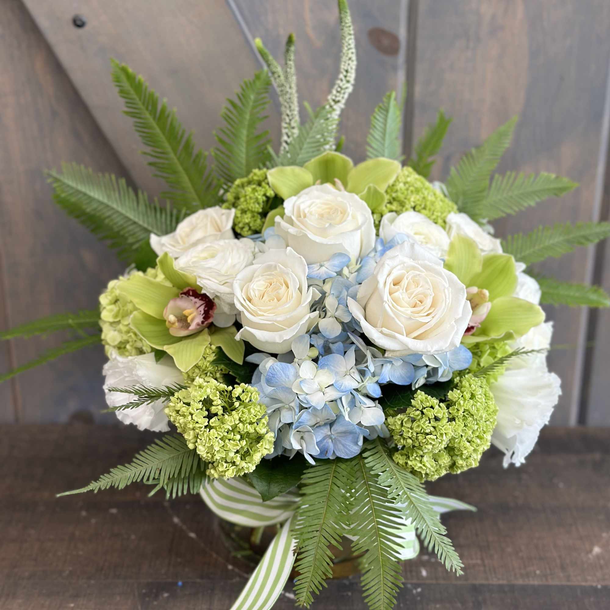 This beautiful arrangement including Hydrangea, Roses, Cymbidium Orchids, Ranunculus, Veronica, Lisianthus, Mini