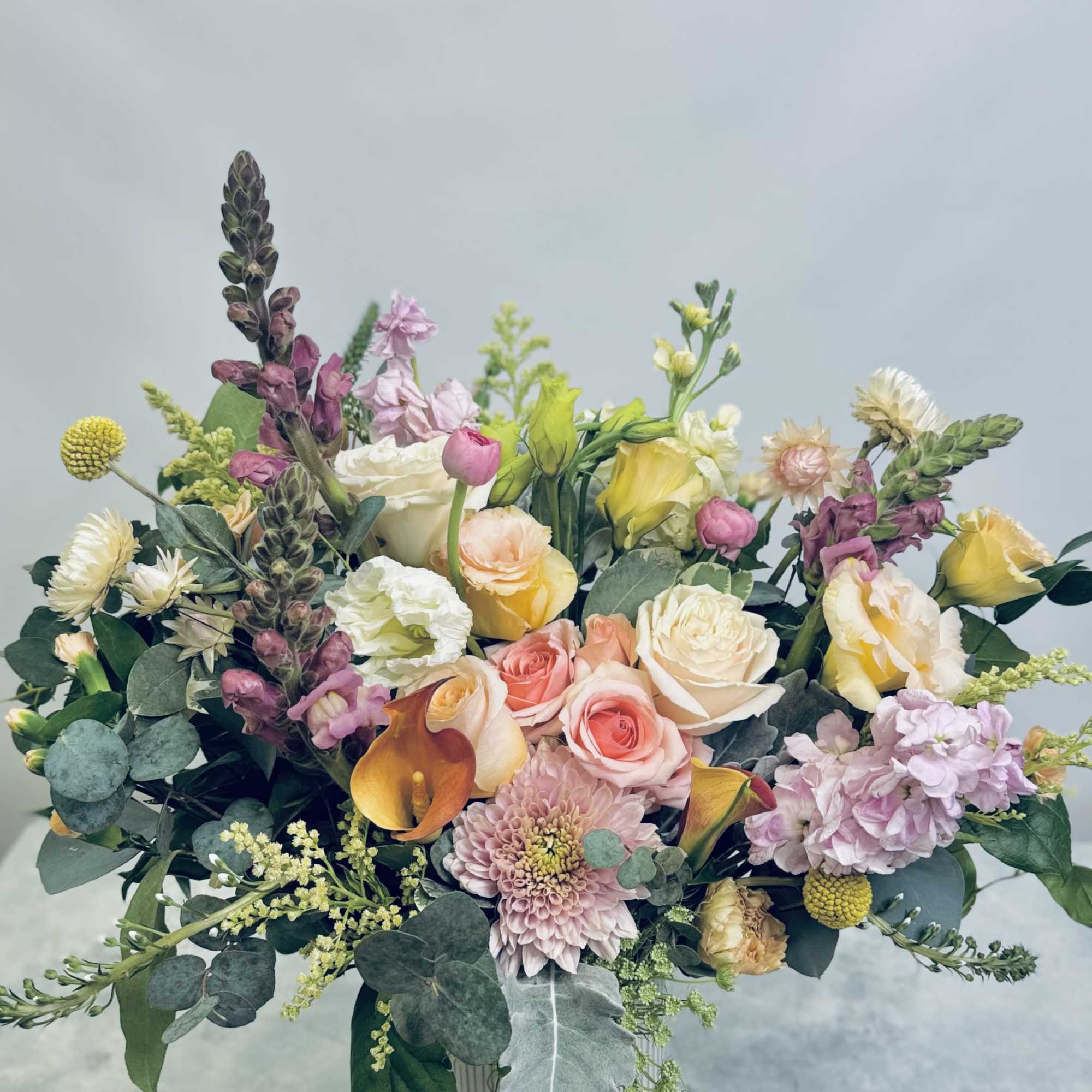 Fresh florals in seasonal hues tucked into botanical greens and eucalyptus in