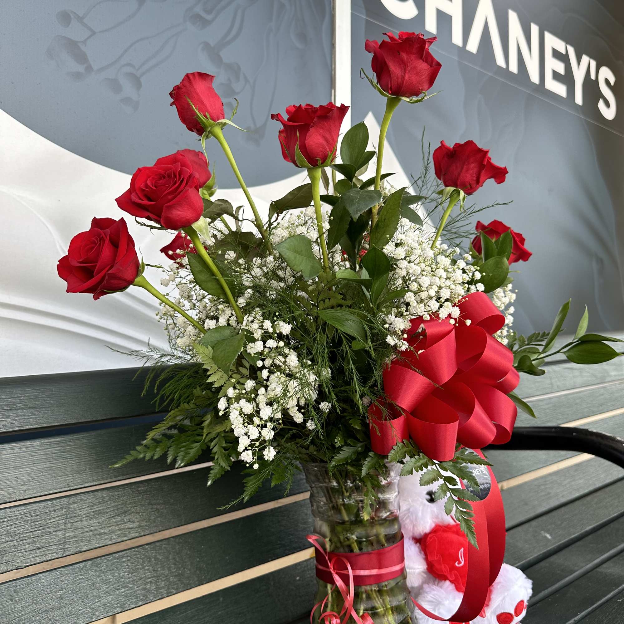 a dozen beautiful red roses arranged with a little green and a