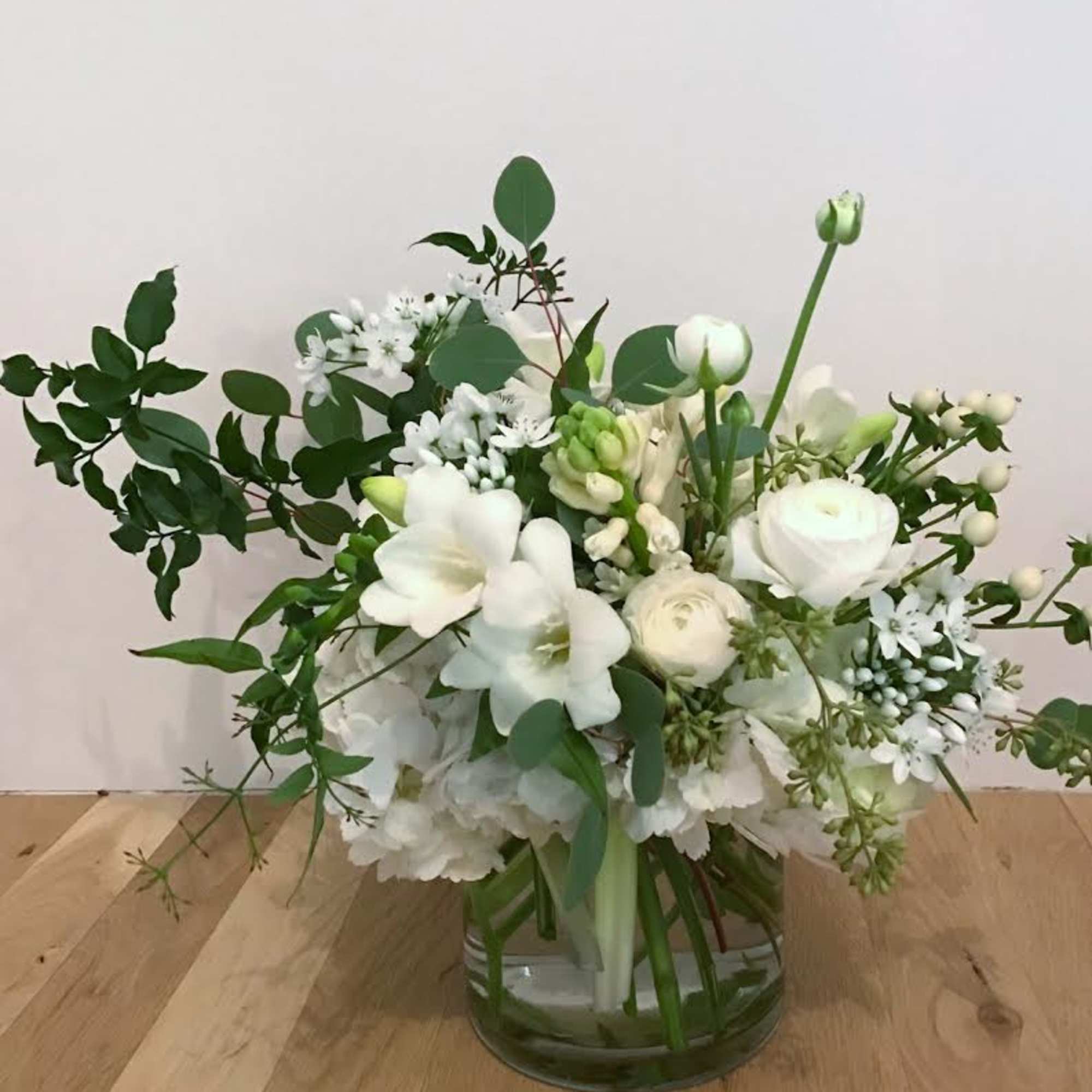 Elegant, soft, and full arrangement featuring larkspur, freesia, lisianthus, and other seasonal