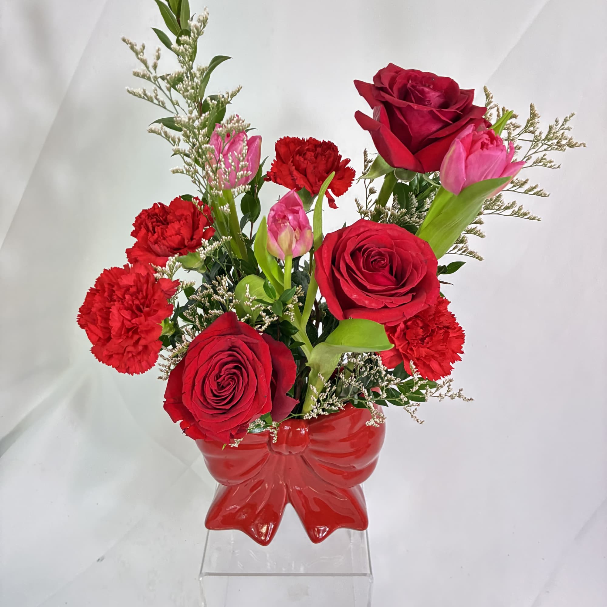 This keepsake red, ceramic, bow vase holds a fresh, fanciful bouquet of