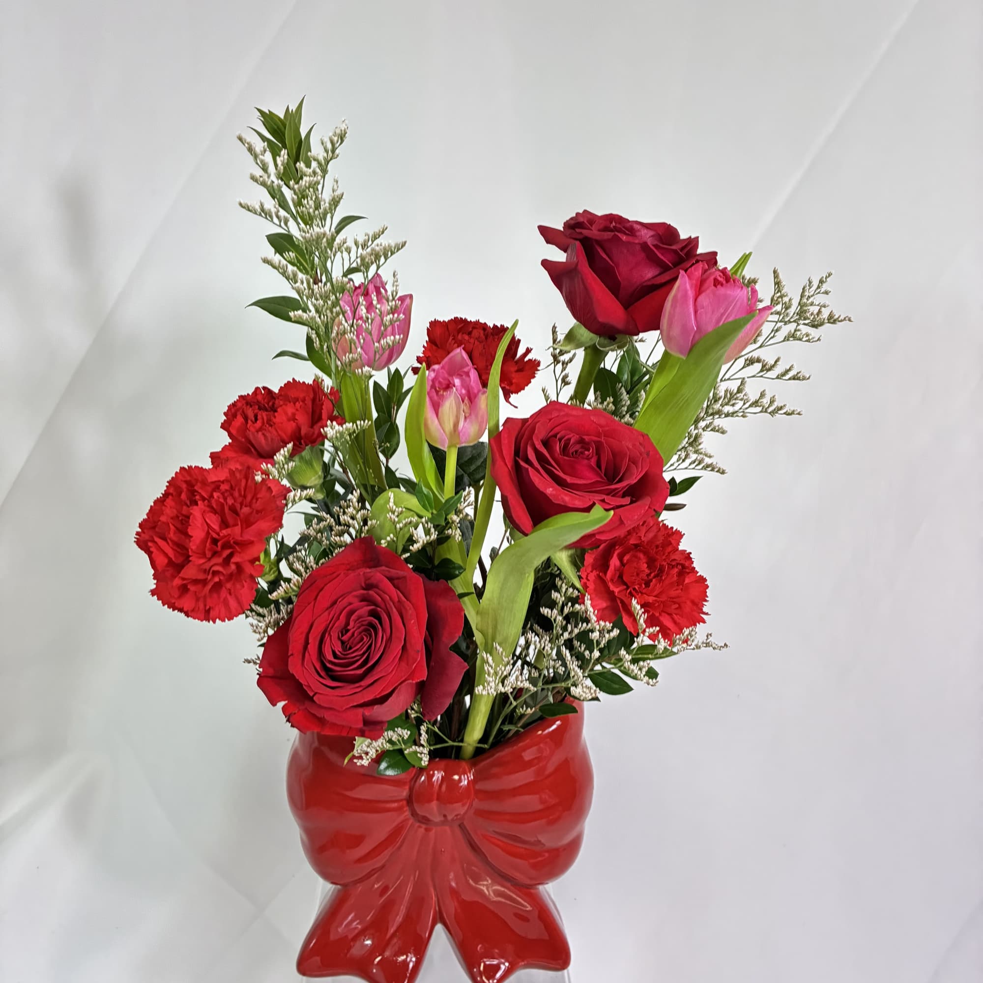 This keepsake red, ceramic, bow vase holds a fresh, fanciful bouquet of