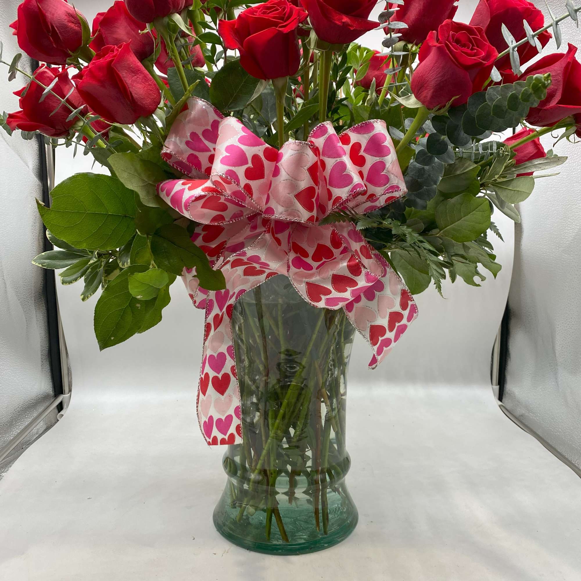 Three dozen long-stemmed red roses in a striking glass vase. 
(Ribbon will